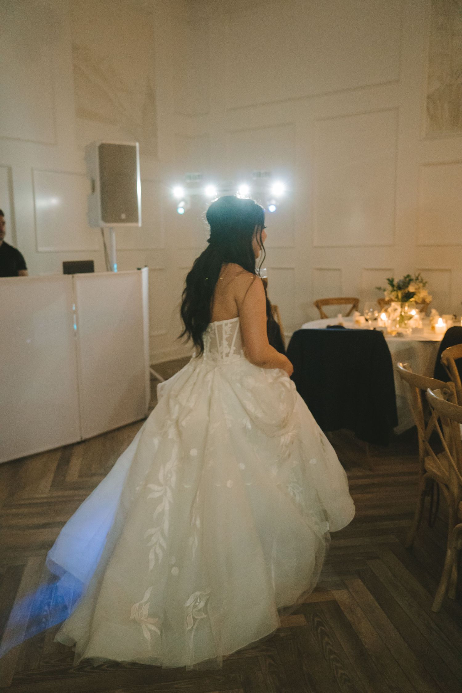 Bride in white ballgown walking across dance floor at wedding reception.