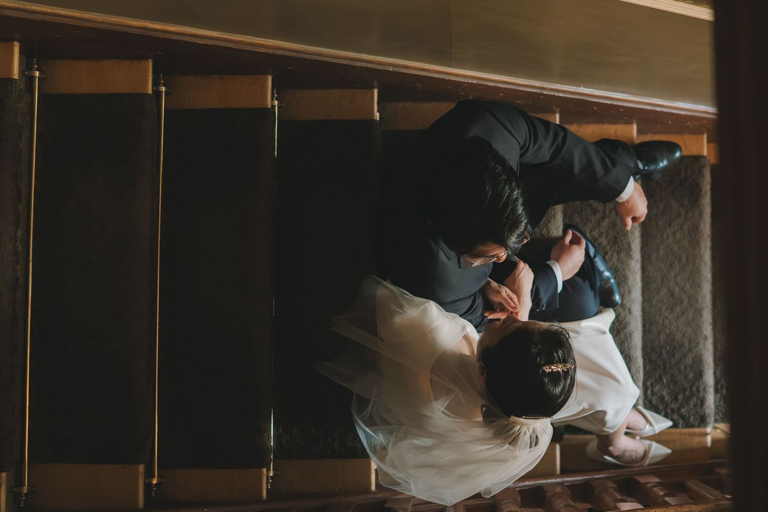 Aerial view of bride and groom sharing romantic moment on staircase at wedding venue.