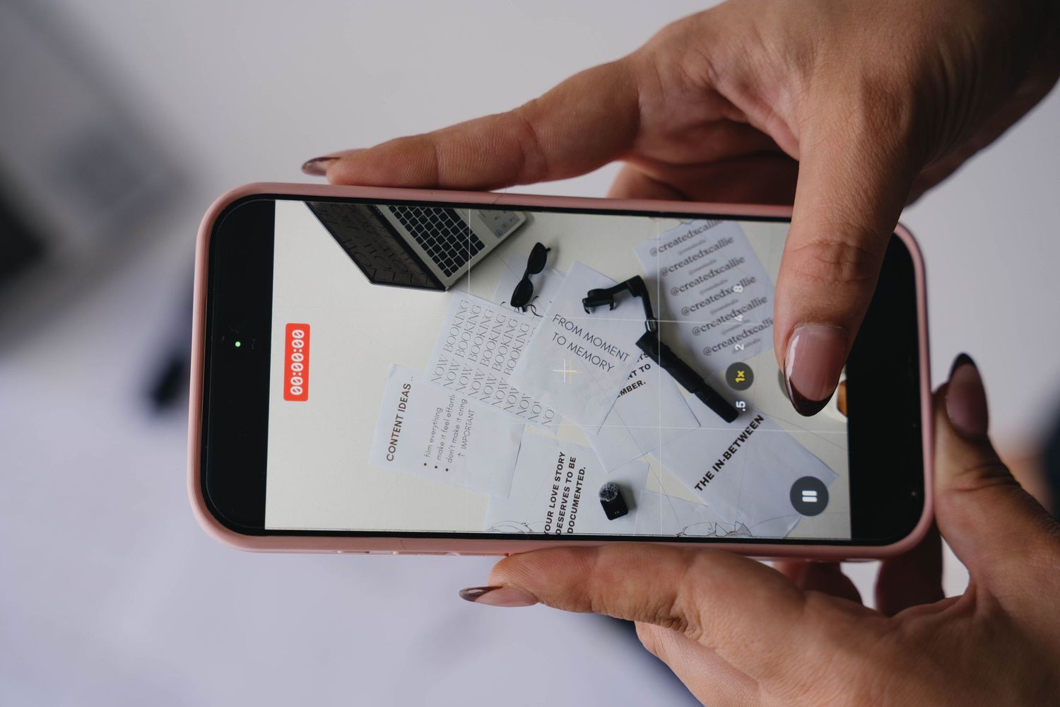 Hands holding a pink iPhone displaying a shopping app with product images on the screen.