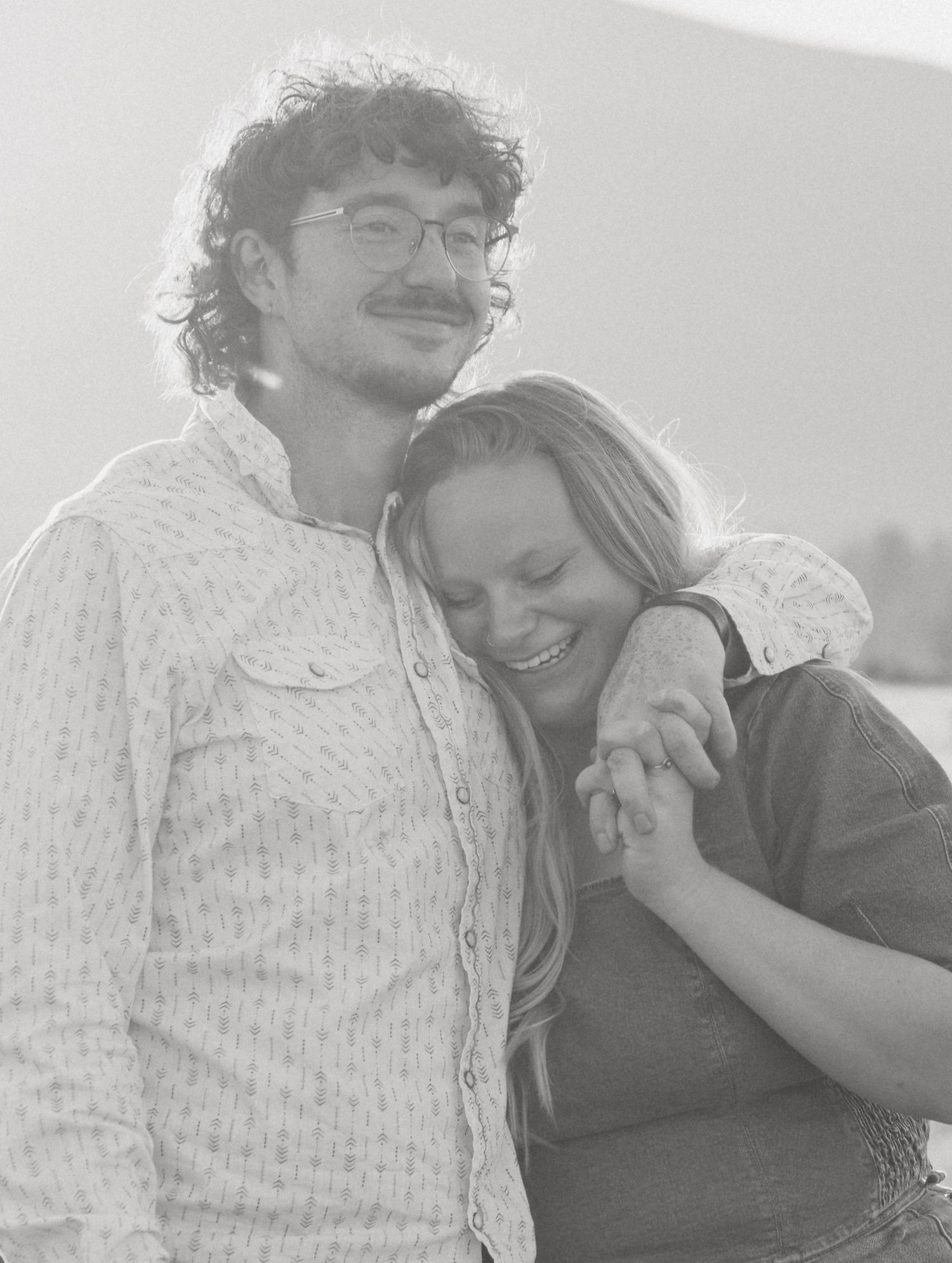 Black and white portrait of a smiling couple sharing a tender moment outdoors.