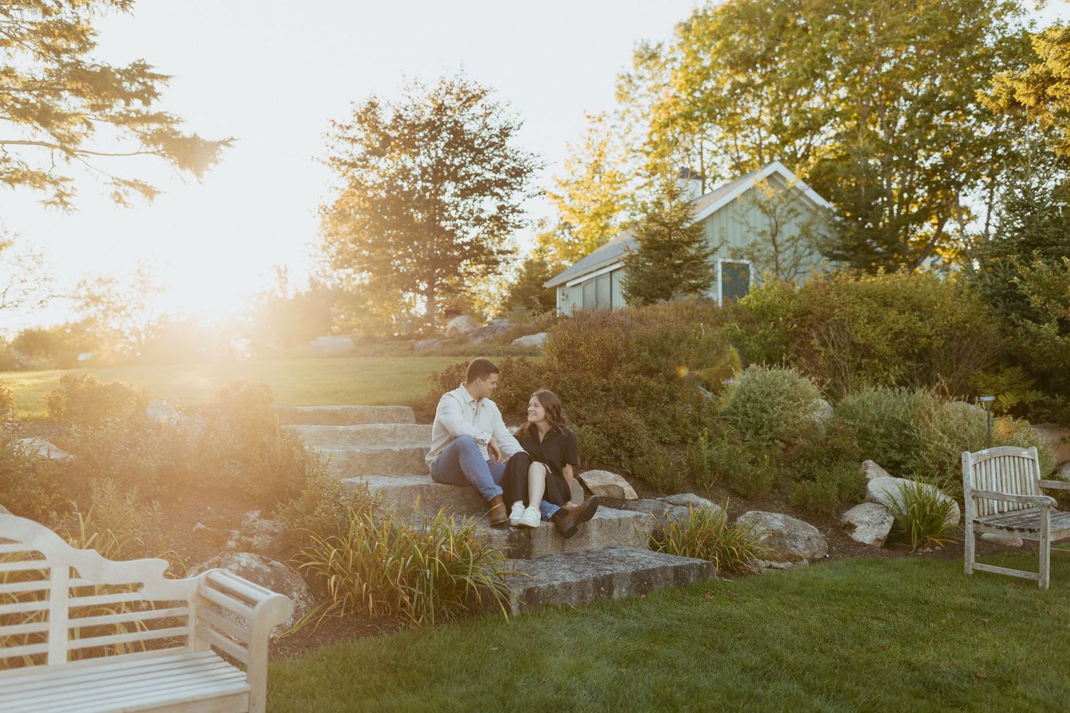 Couple relaxing on stone garden steps bathed in warm golden sunset light outdoors.