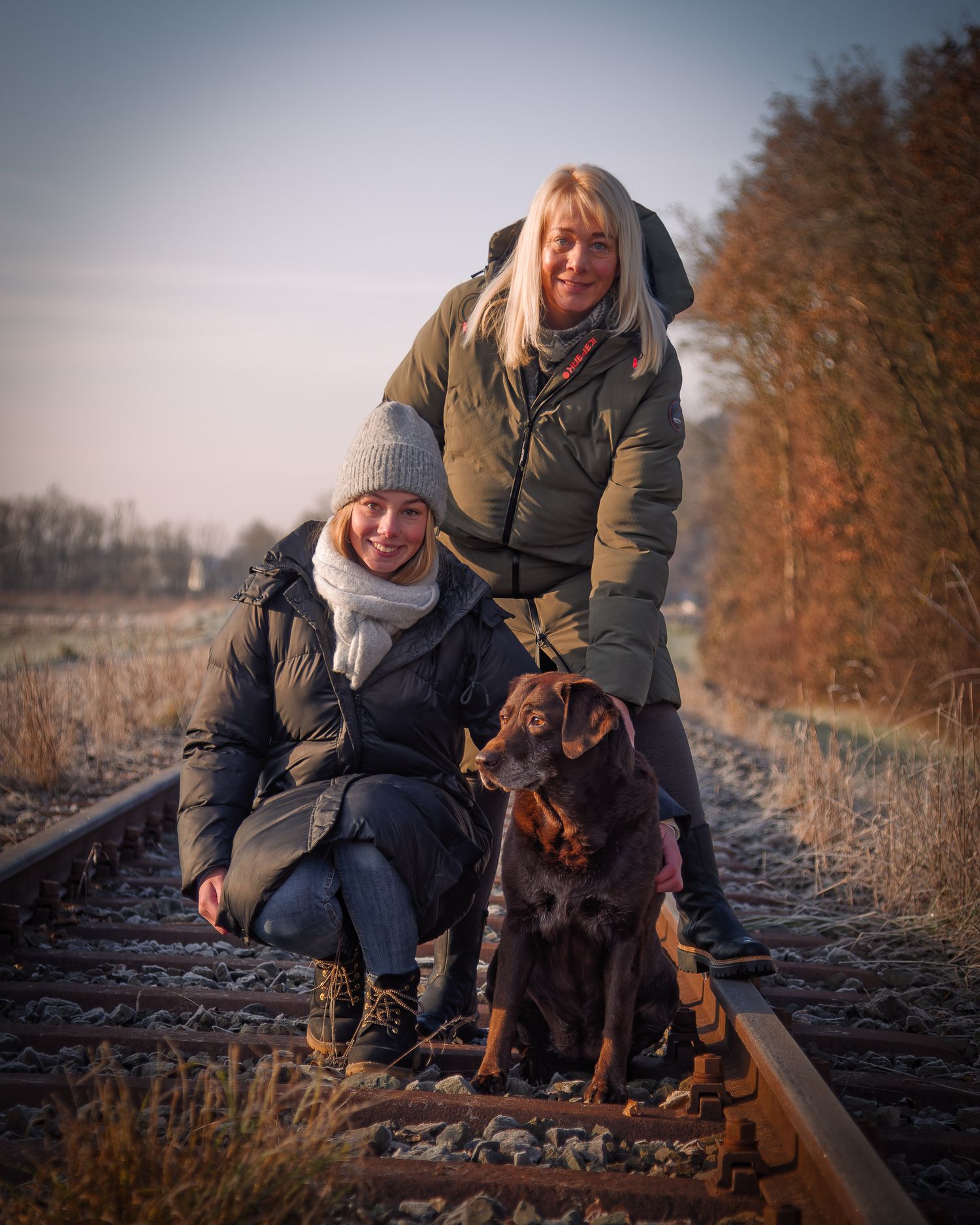 Paar mit Hund bei einem natürlichen Fotoshooting im Freien auf alten Gleisen. Authentische Tier- und Familienfotografie in der Region Forchh