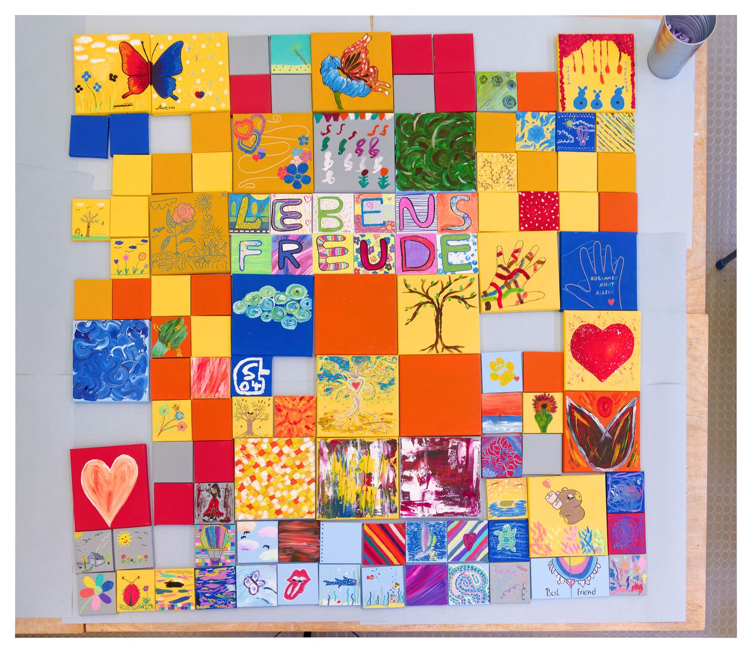Farbenfrohes Mosaikkunstwerk mit bemalten Fliesen, die LEBENSFREUDE buchstabieren, mit lebhaften Mustern, Herzen und Naturmotiven