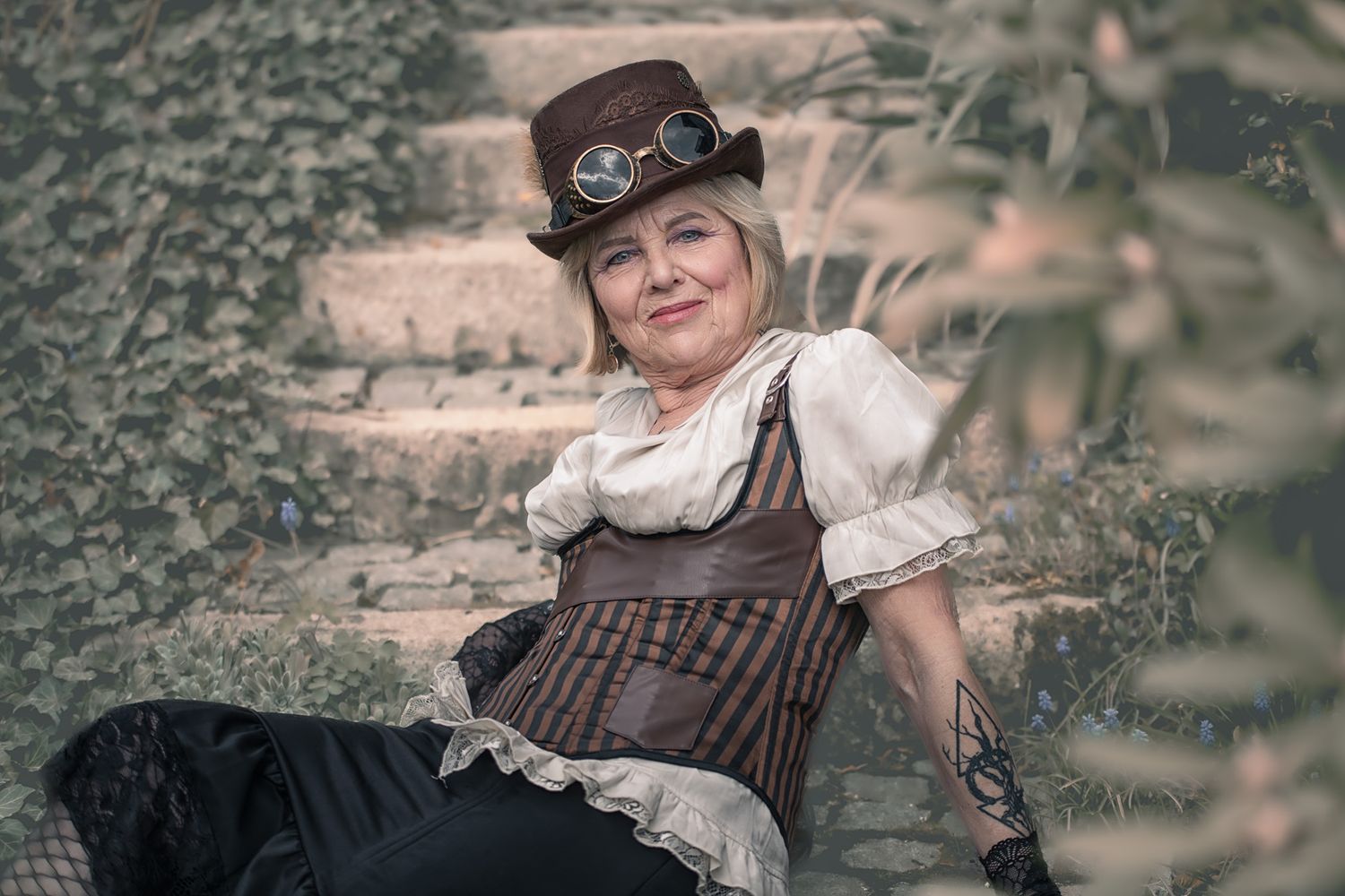 Kreatives Charakterporträt einer Frau im Steampunk-Outfit auf Steinstufen. Ausgefallene und authentische Porträtfotografie in Pegnitz