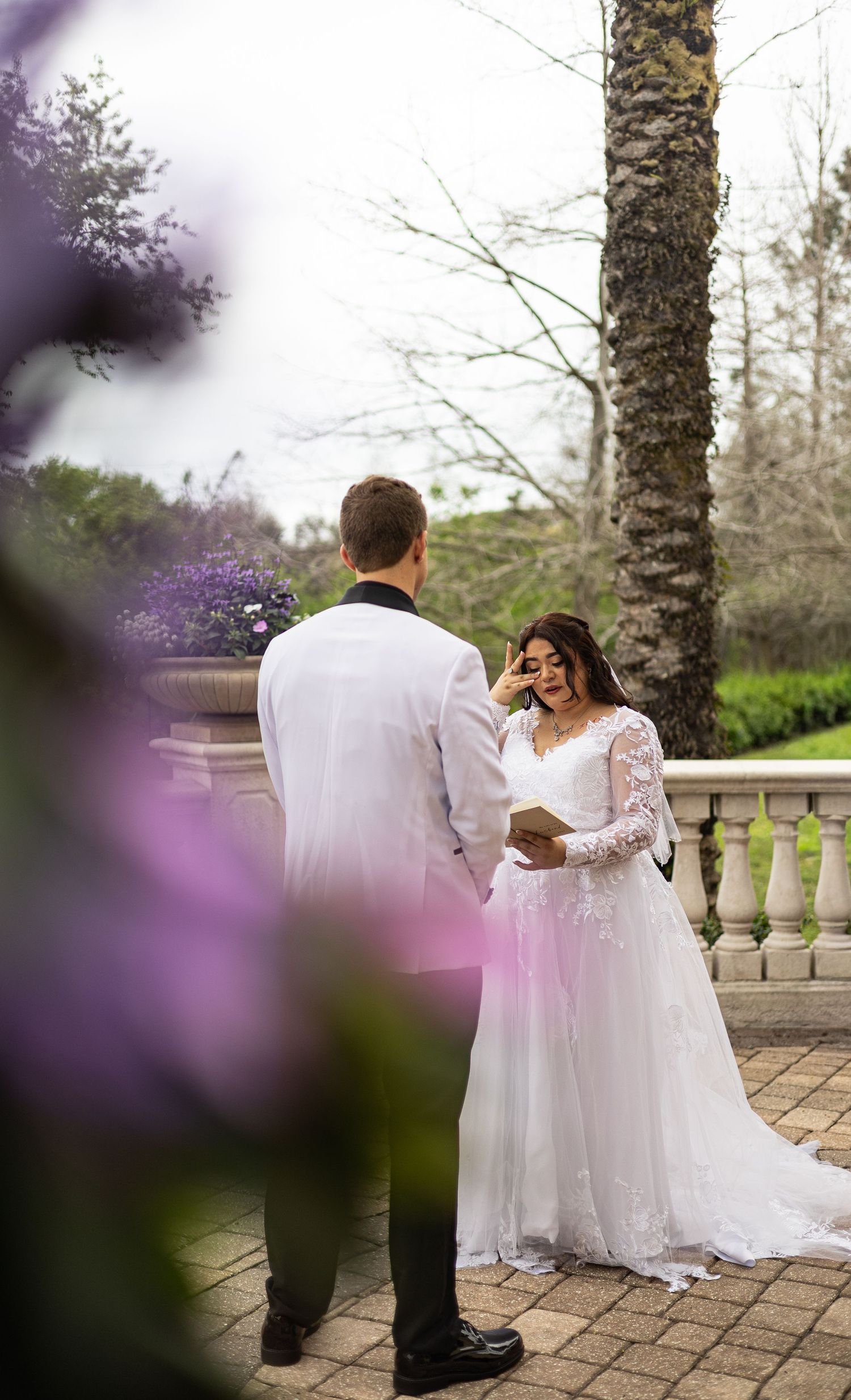 Couple in wedding attire standing among trees and purple flowers.    Orlando FL Wedding Photographer