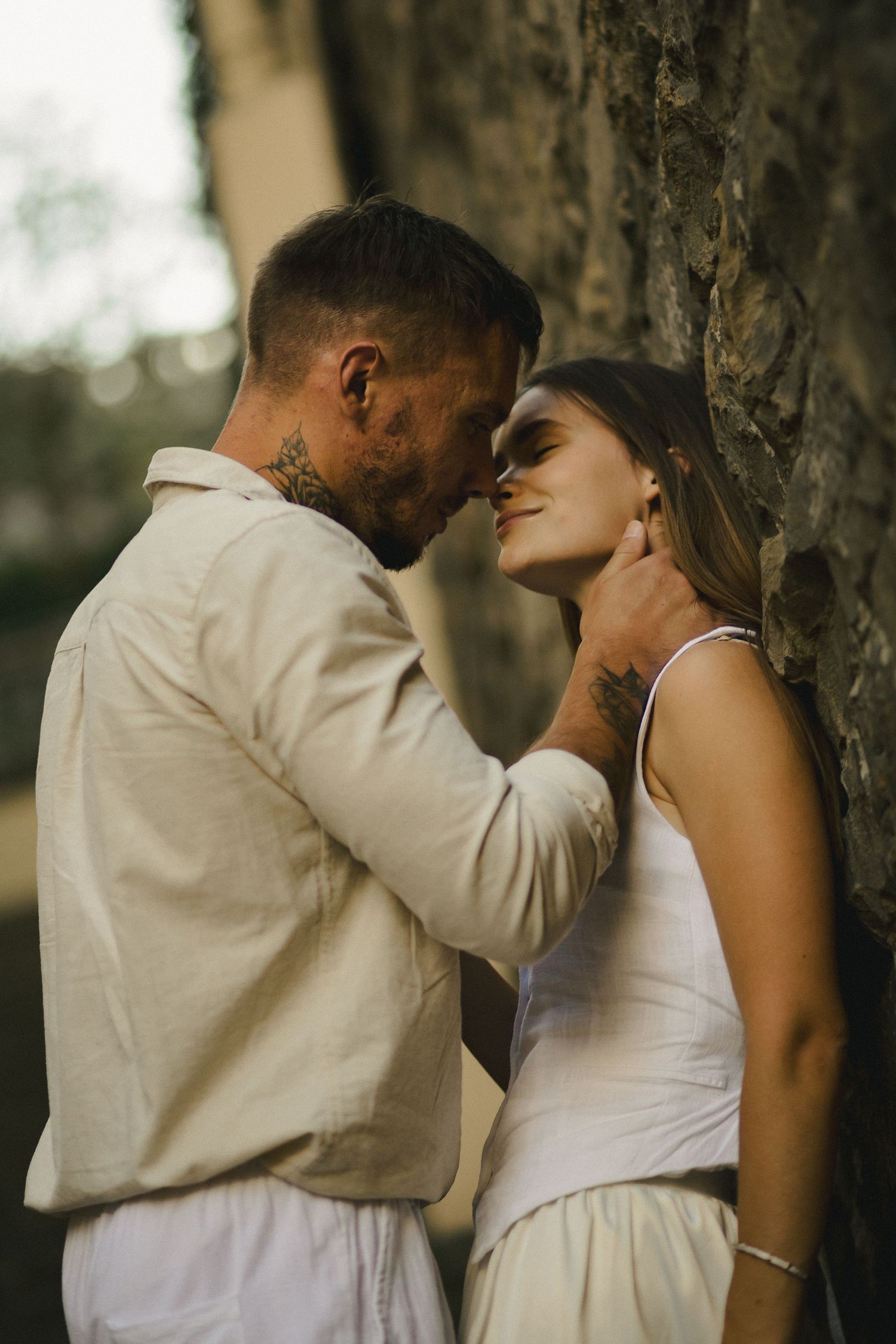 Couple standing close together beneath a tree