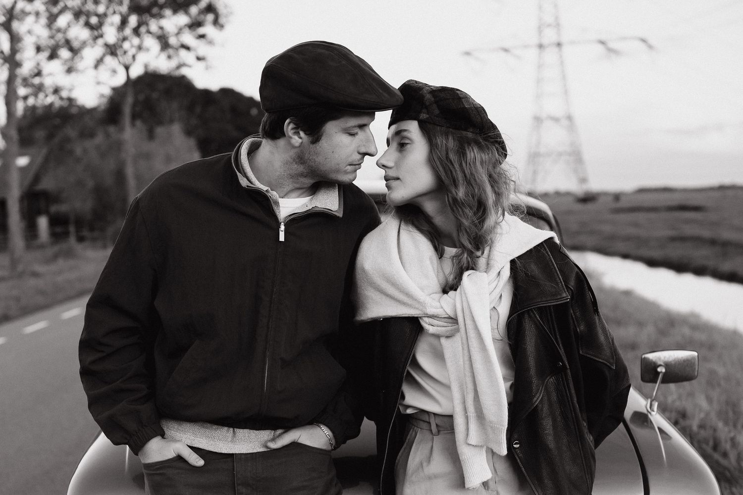 Black and white portrait of a couple beside a vintage car