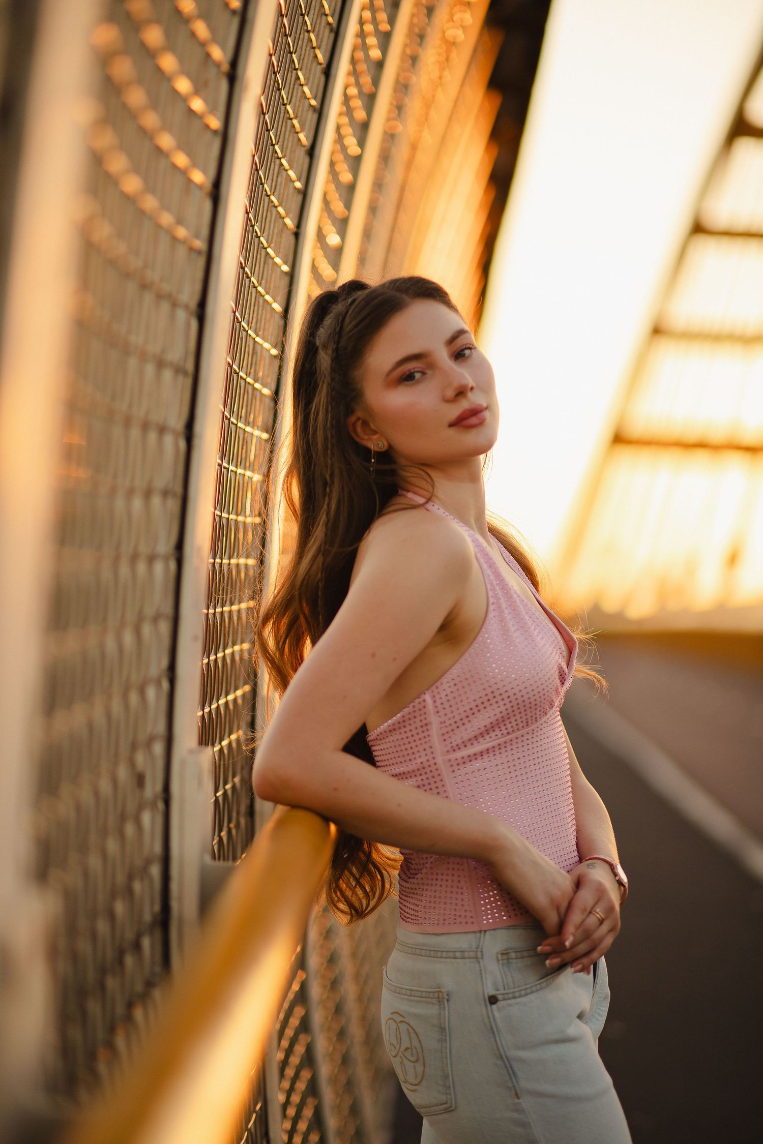 Woman posing by a brick wall at sunset