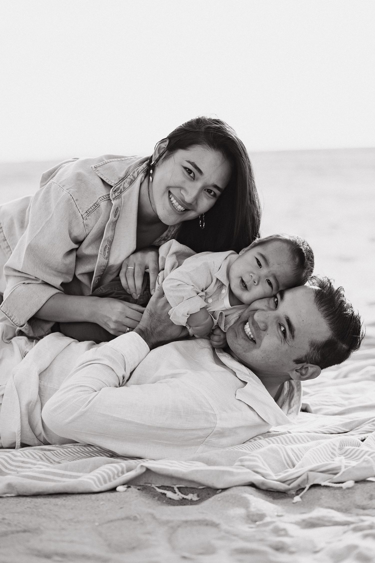 Family lying together on a blanket at the beach
