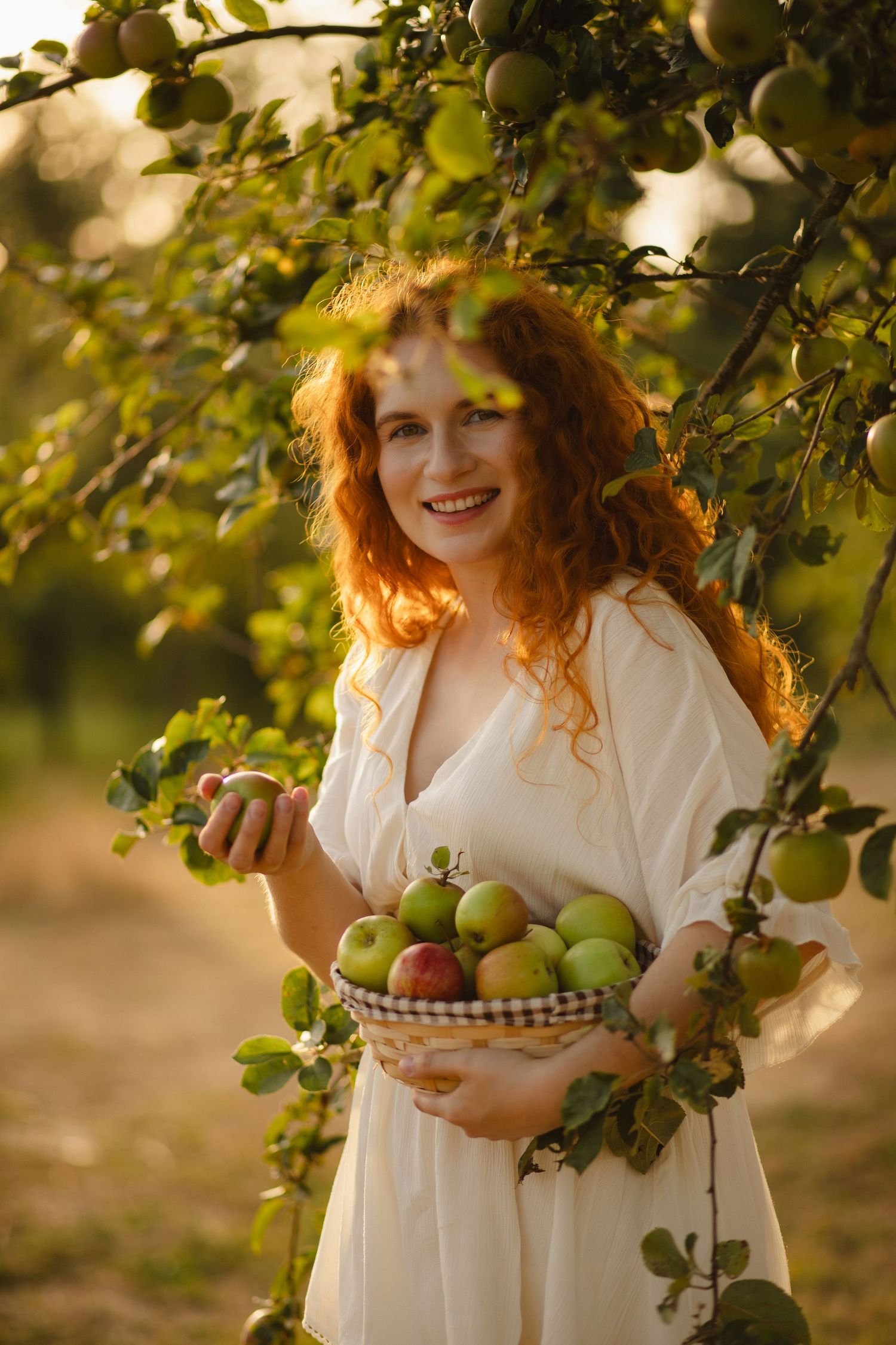 Woman holding a basket of apples in an orchard
