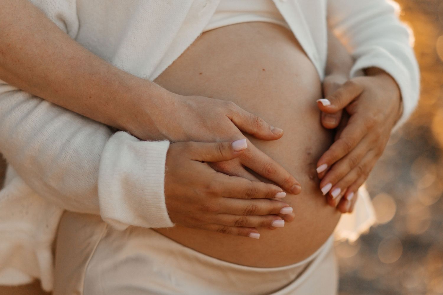 Expectant parents gently holding a pregnant belly