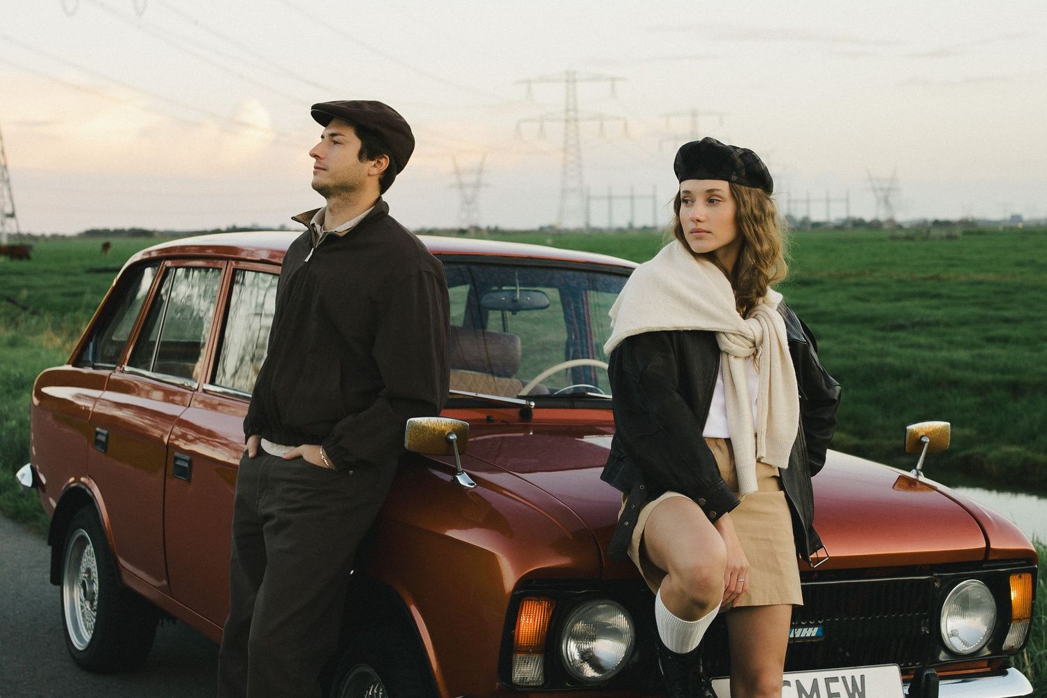 Couple standing beside a vintage car in the countryside