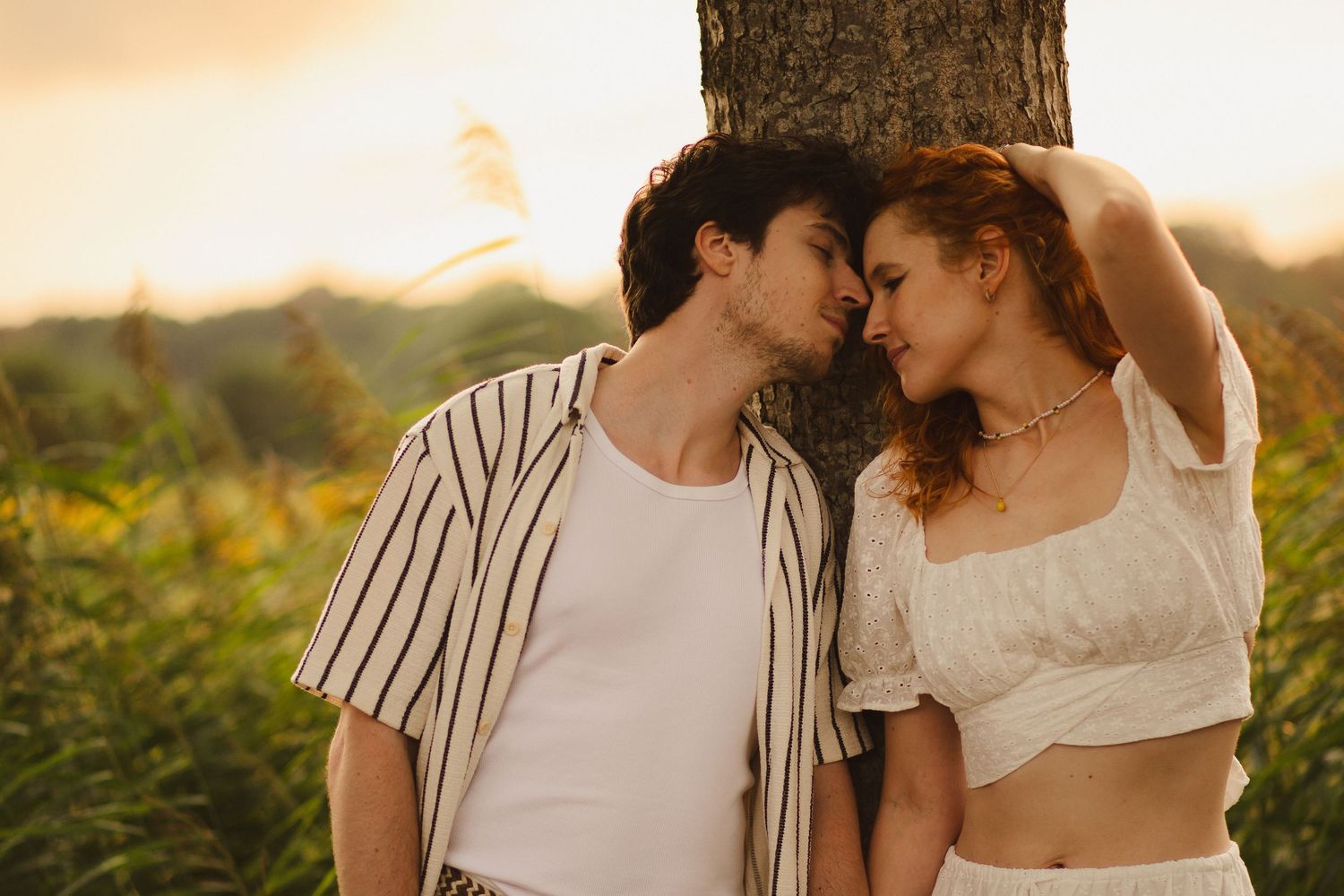 Couple leaning together beneath a tree in the evening light