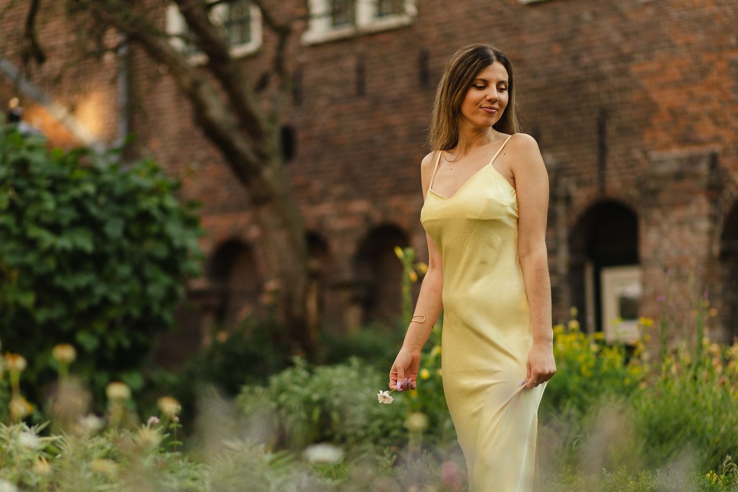 Woman in a yellow dress walking through a garden