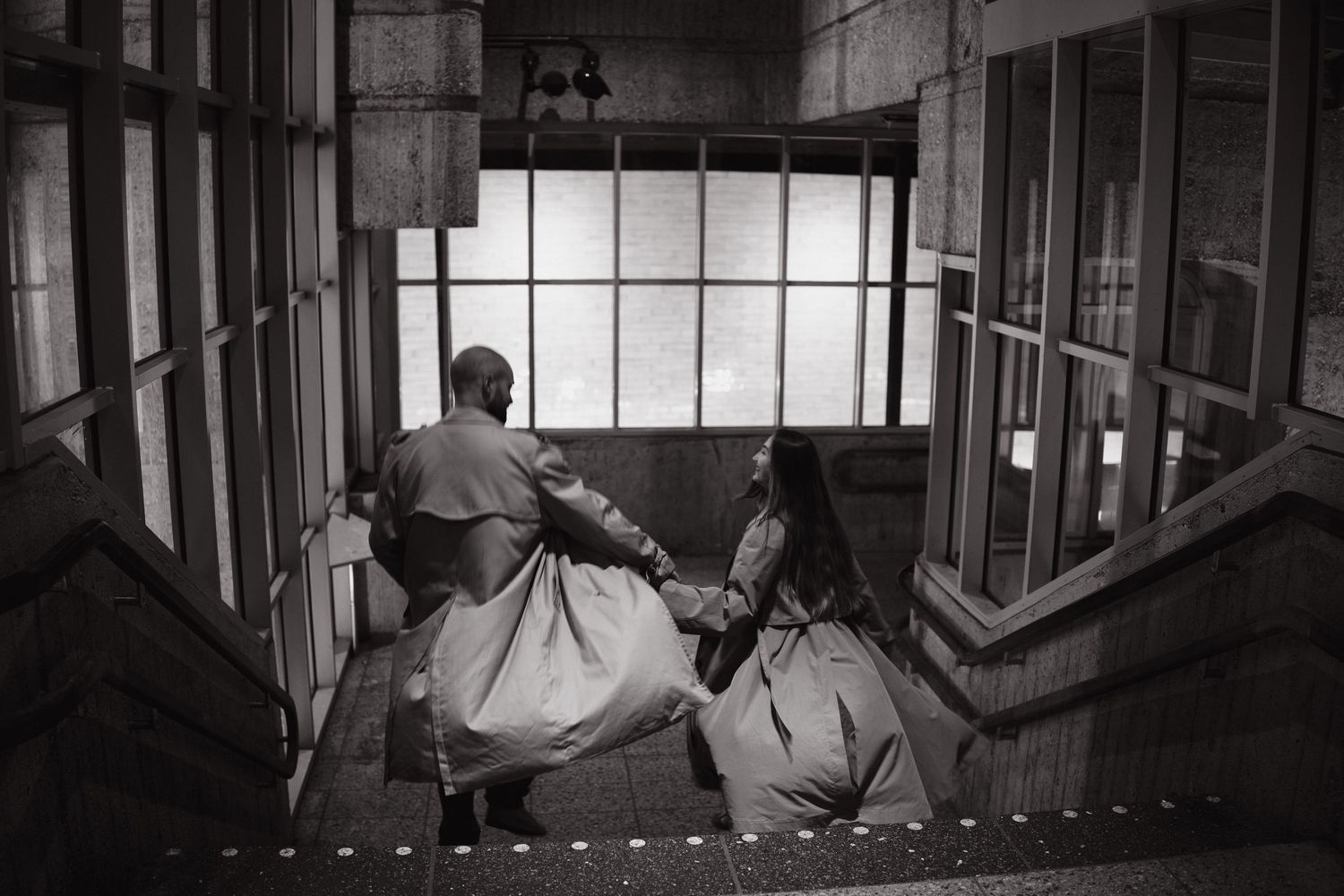 Black and white photo of a couple walking down a staircase