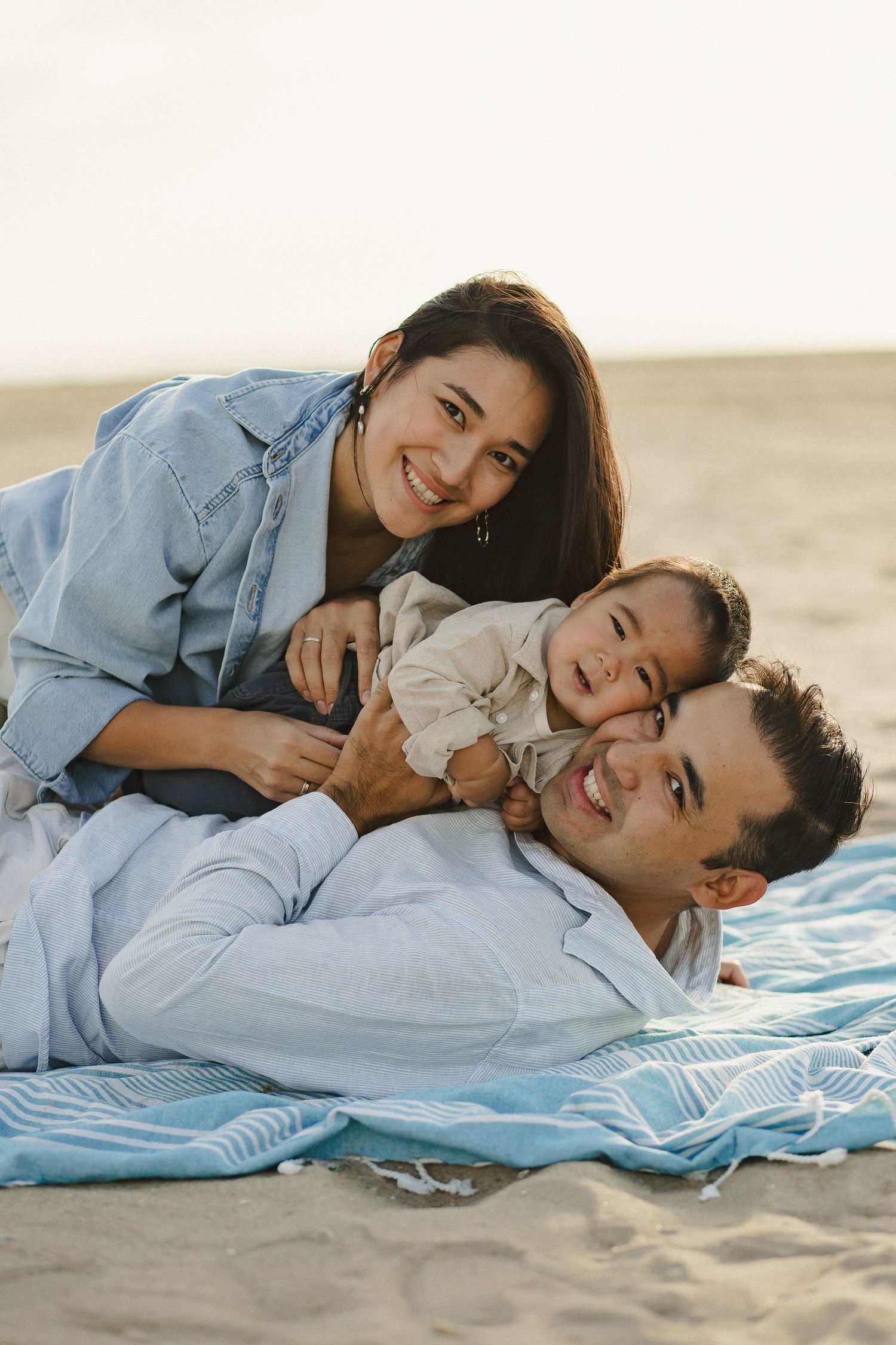 Family lying together on a blanket at the beach