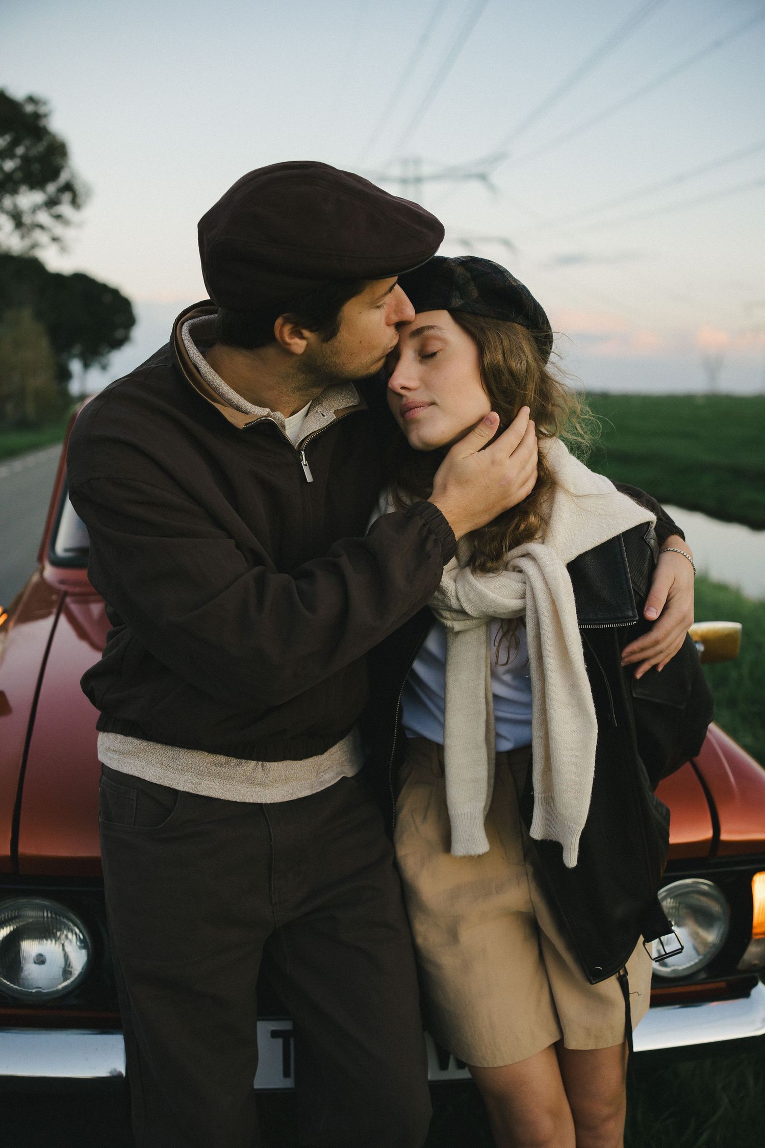 Couple sharing a kiss beside a vintage car
