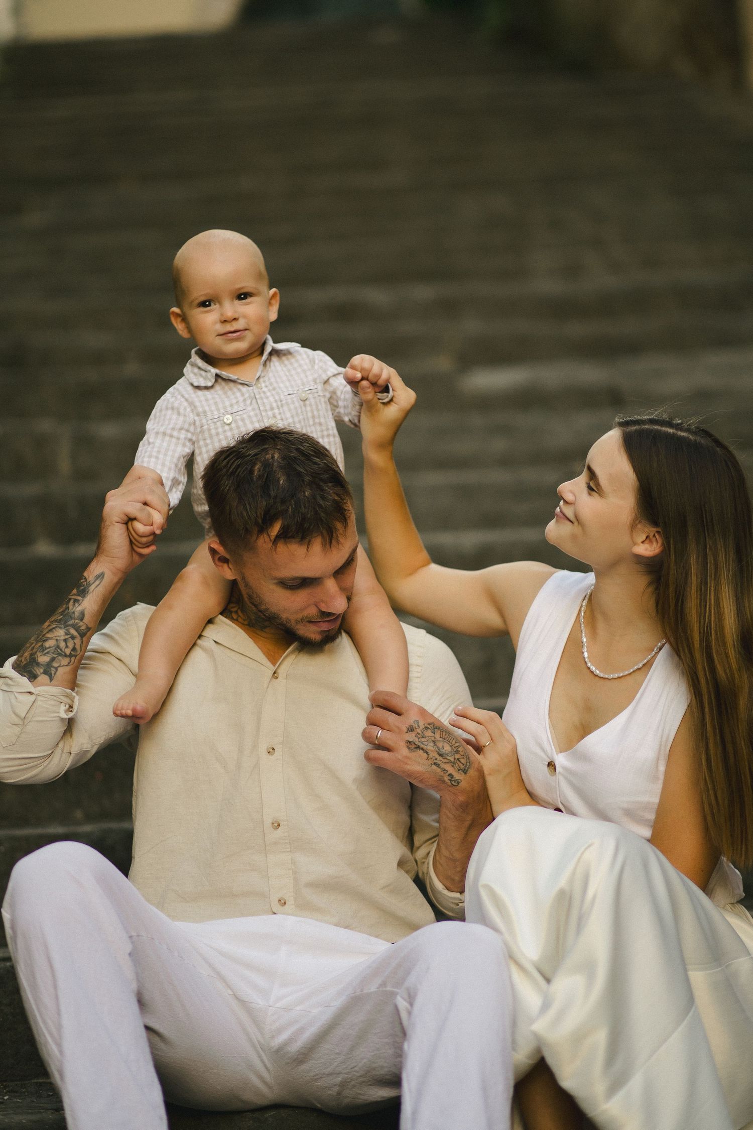 Parents sitting together while their baby plays on their shoulders