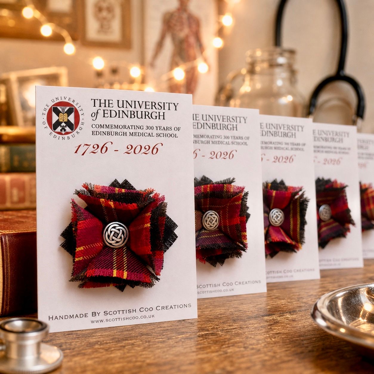 Handmade red tartan fabric rosette brooches on University of Edinburgh 1726-2026 Medical School bicentenary cards by Scottish Cod Creations.