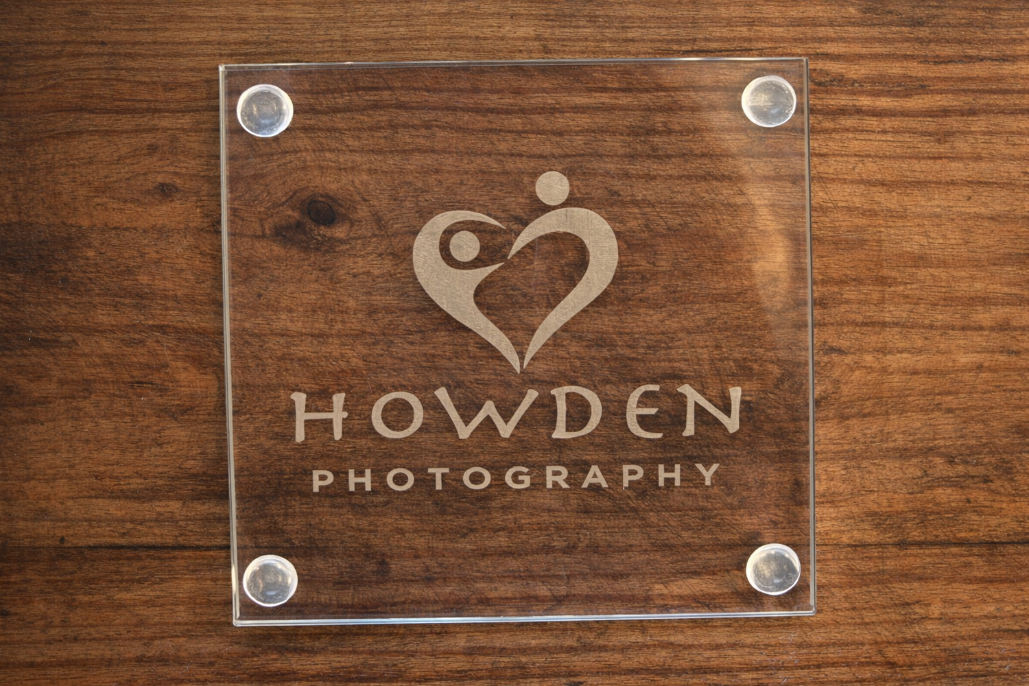 A rustic wooden wall with mounted glass business signs displaying company names and logos.