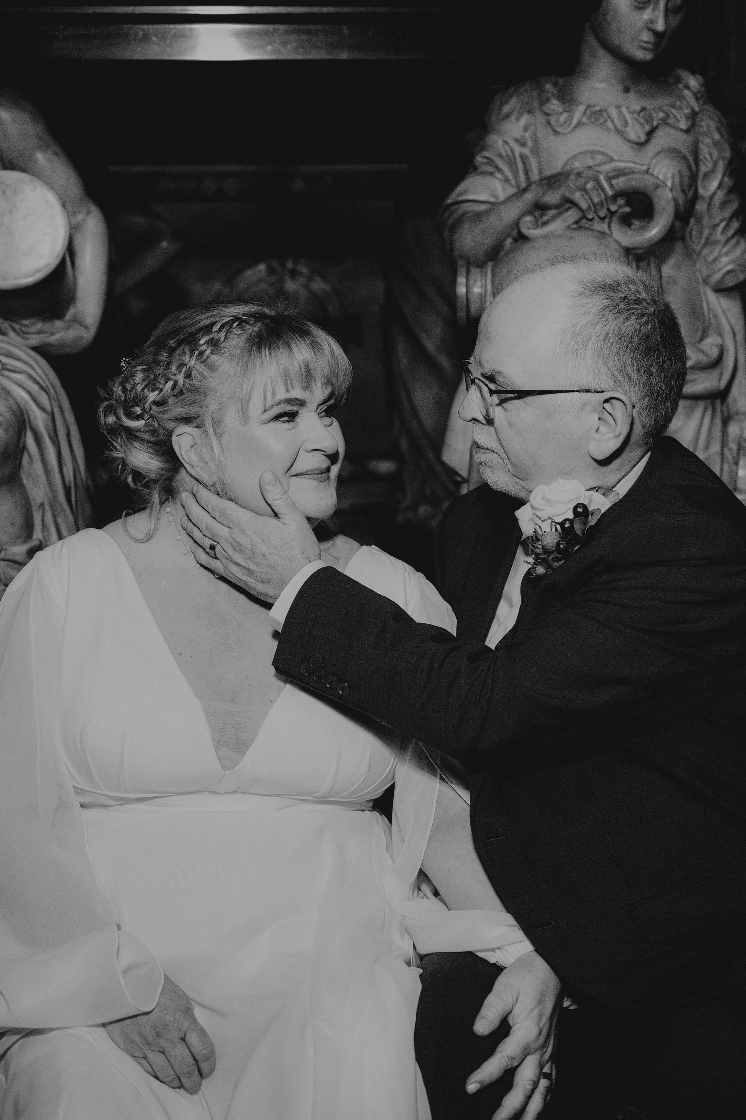 A vintage black and white photograph shows an intimate moment between a couple during what appears to be a wedding celebration.