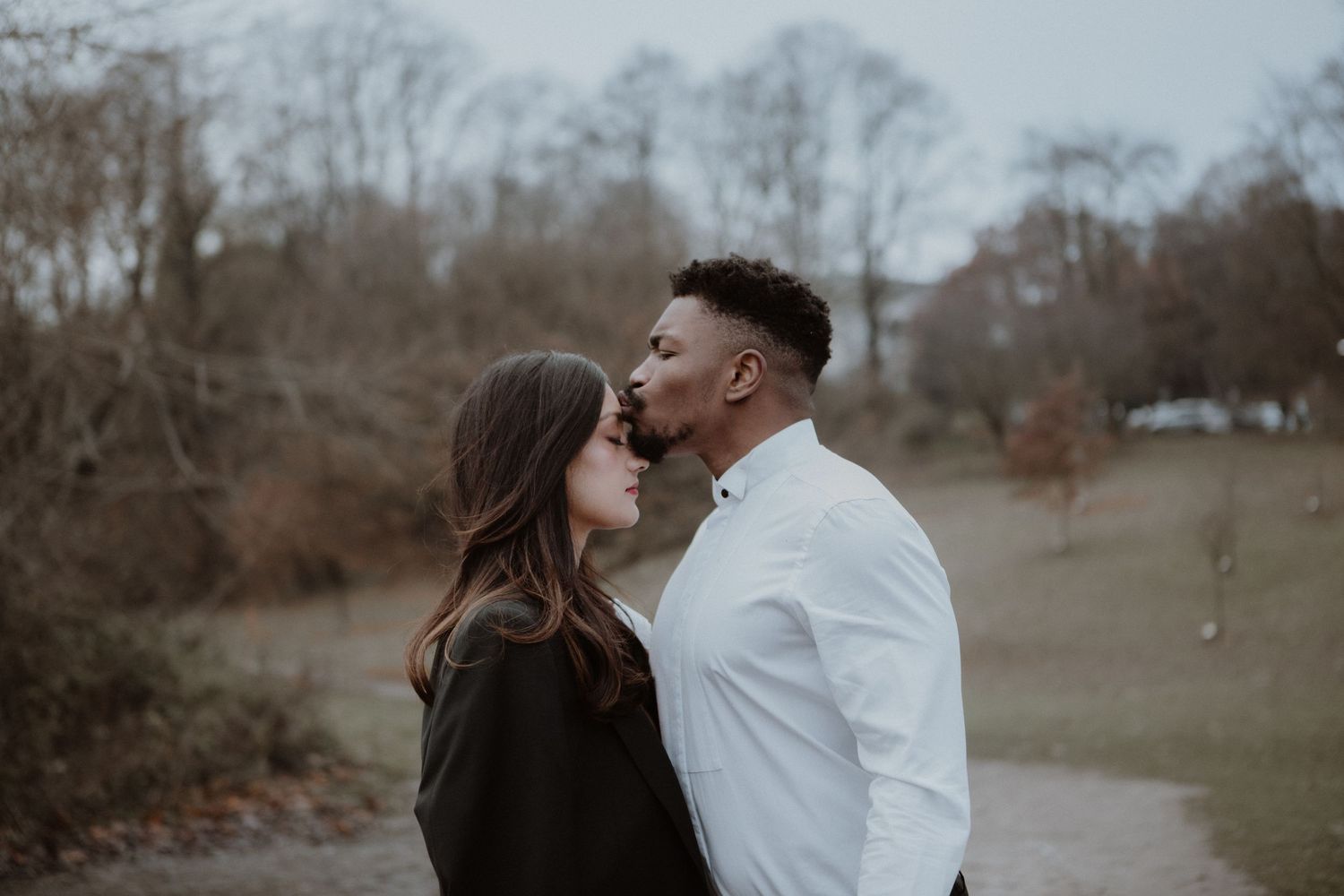 A tender romantic moment between a couple sharing an intimate kiss outdoors.