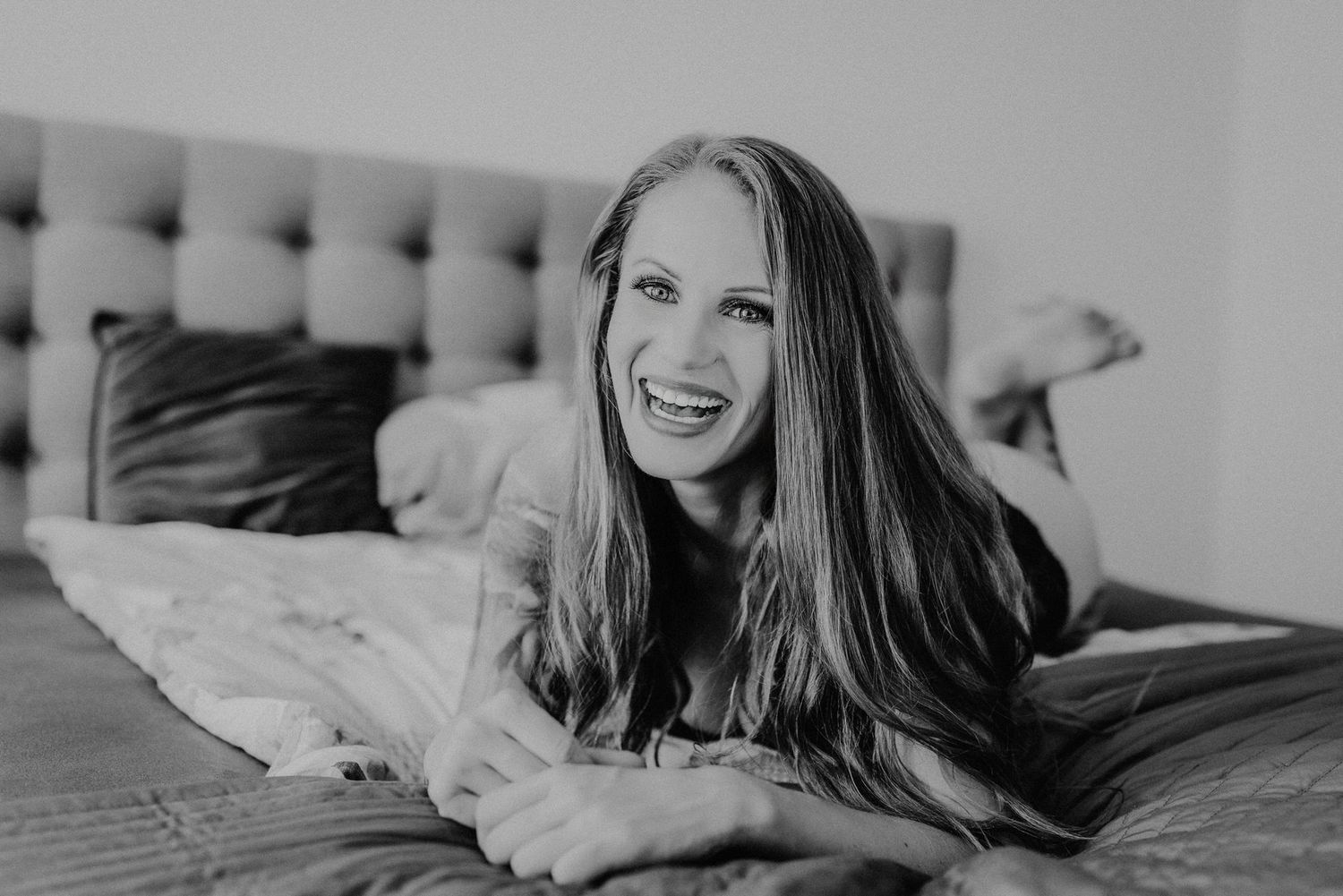 Schwarz-Weiß-Fotoserie, die eine Frau zeigt, die sich entspannt und lächelt, während sie auf einem Bett liegt.
