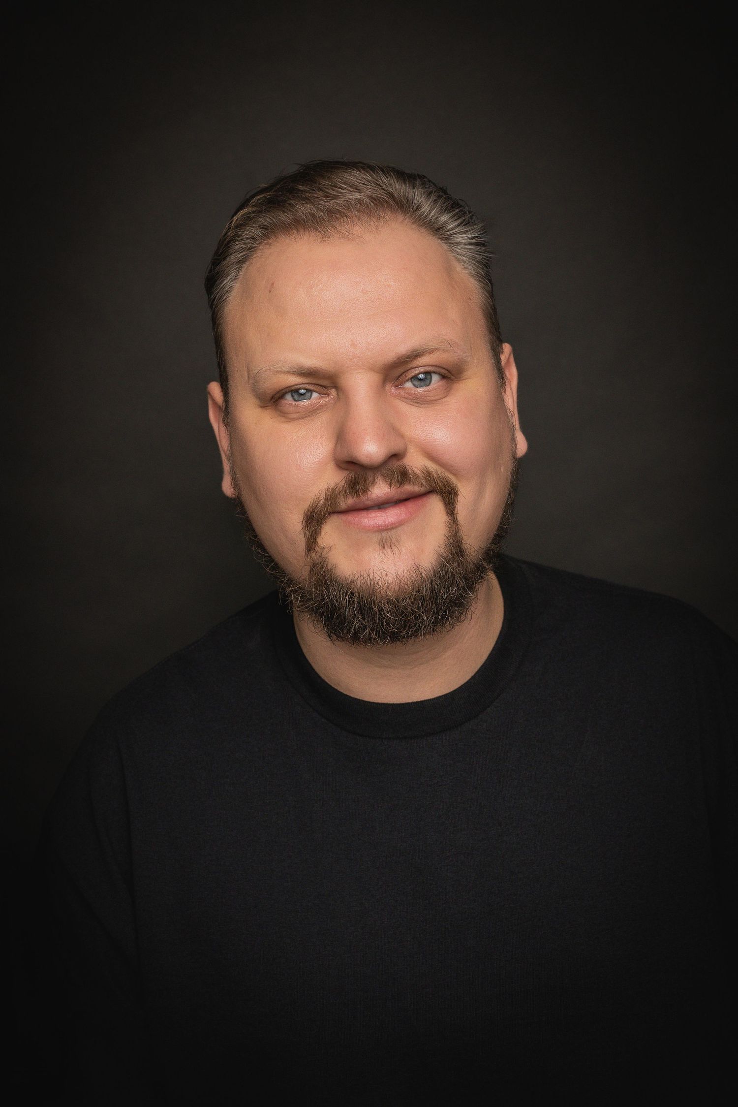A dramatic studio portrait series against a dark background shows someone with a beard wearing black clothing.