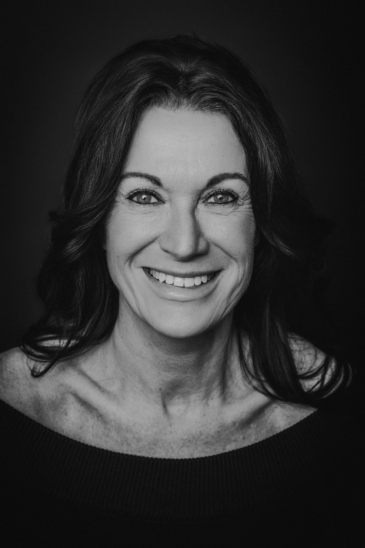 A series of black and white portraits showing joyful expressions and genuine smiles in dramatic lighting.