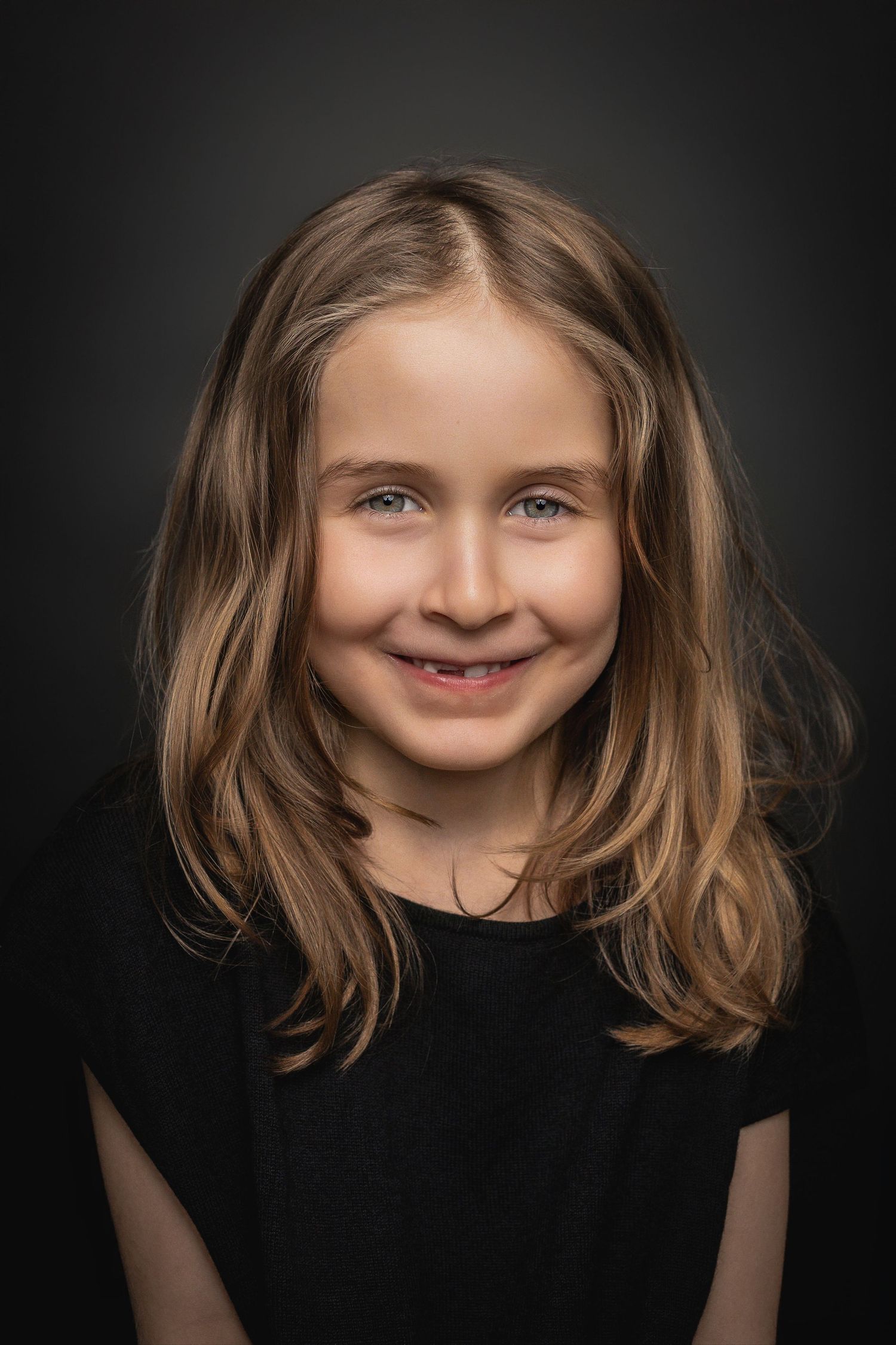 A series of close-up portraits showing a child with brown hair wearing a black shirt against a dark background.