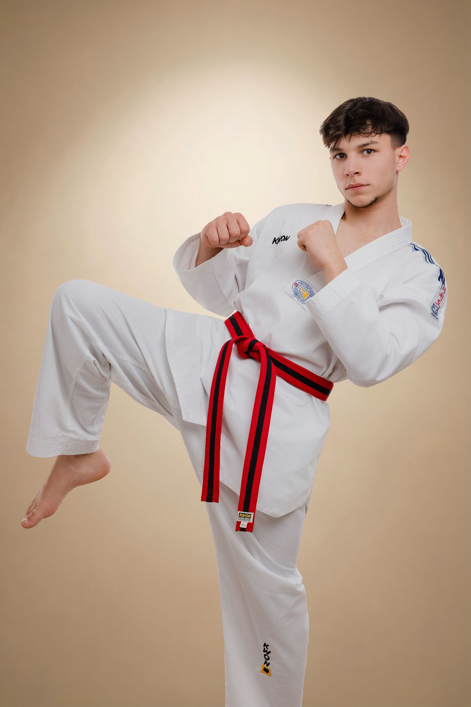 A martial artist in a white uniform demonstrates a high side kick sequence against a neutral background.