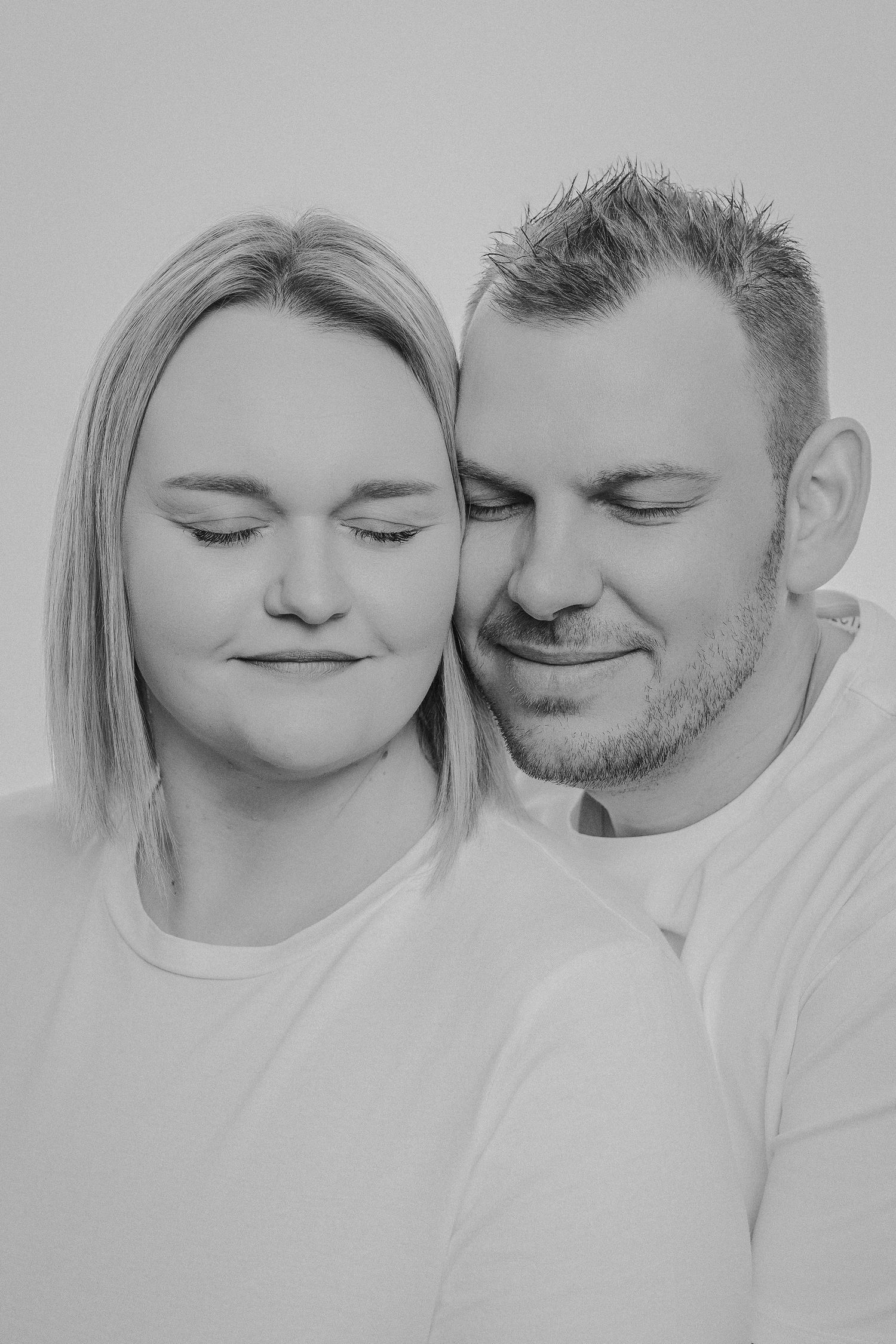 Black and white romantic portrait series showing tender intimate moments between a couple in white clothing.