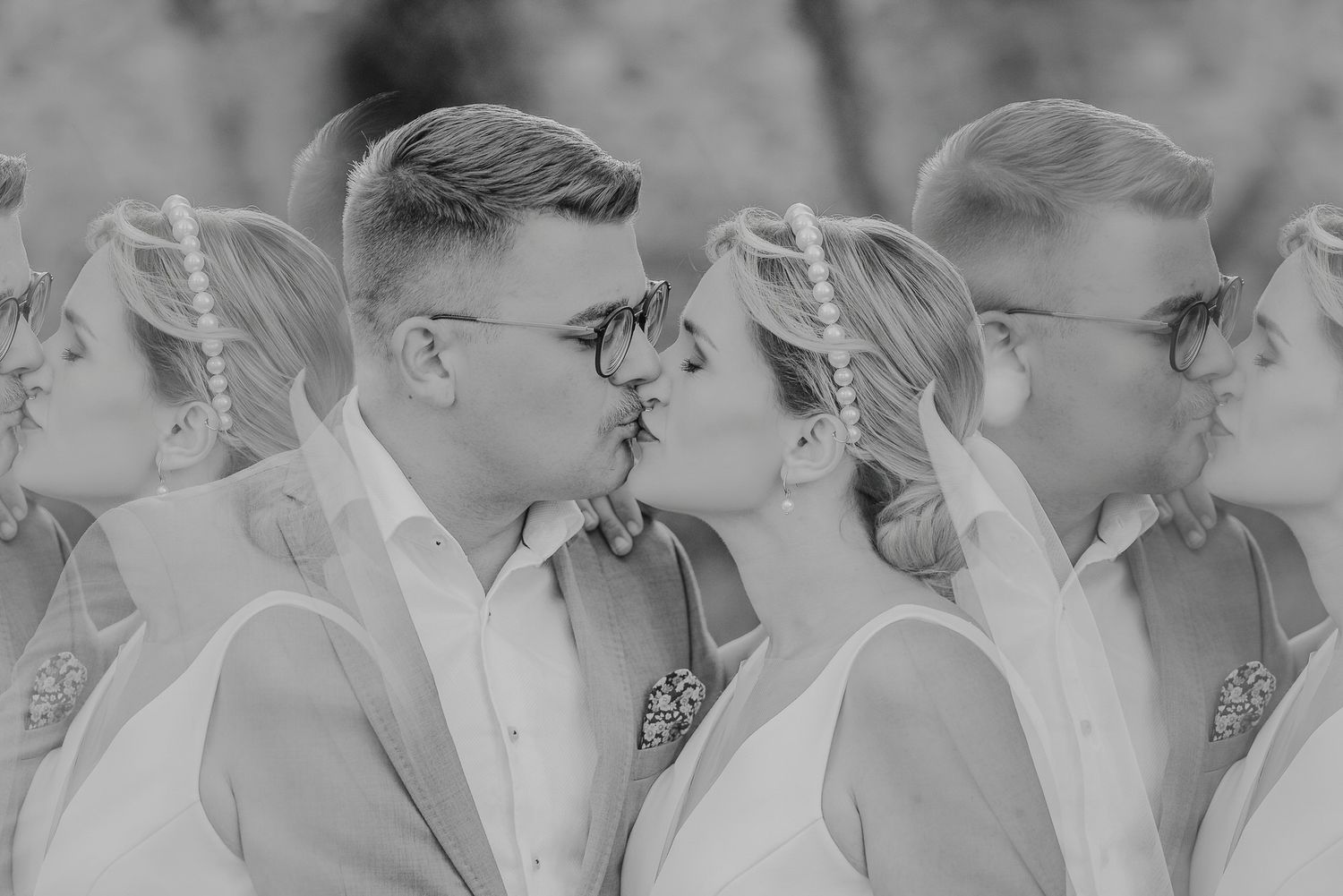 A black and white wedding photograph shows a bride and groom surrounded by their wedding party in formal attire.