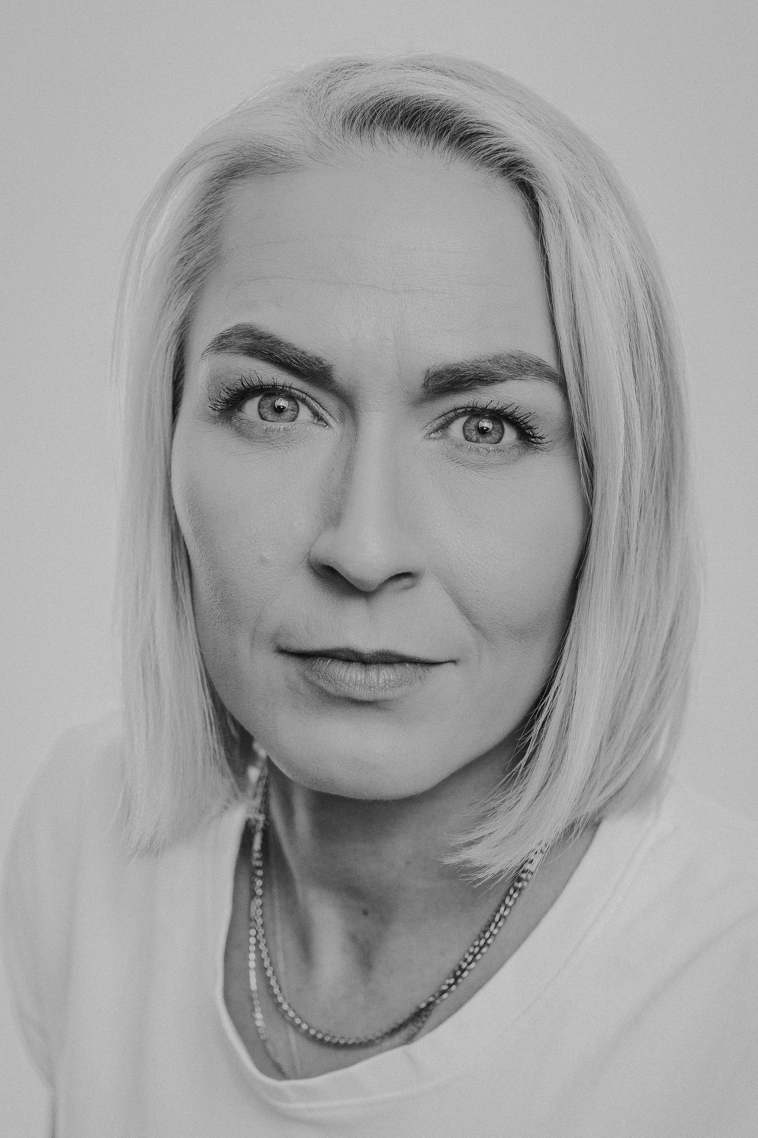 A series of black and white portraits showing different angles of someone with platinum blonde hair and expressive poses.