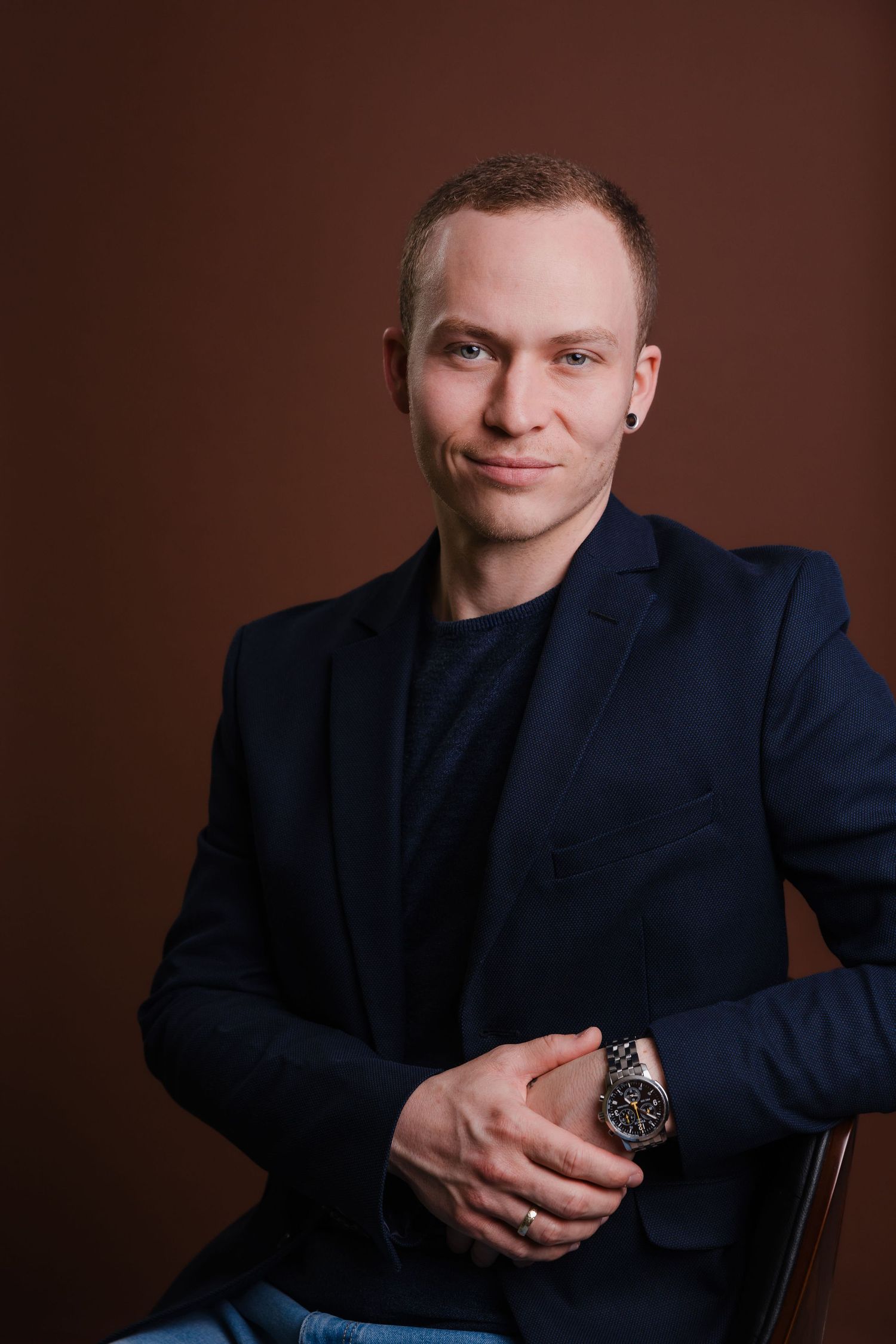 Professional studio portrait series showing a person in a navy suit against a dark brown background with varying poses.