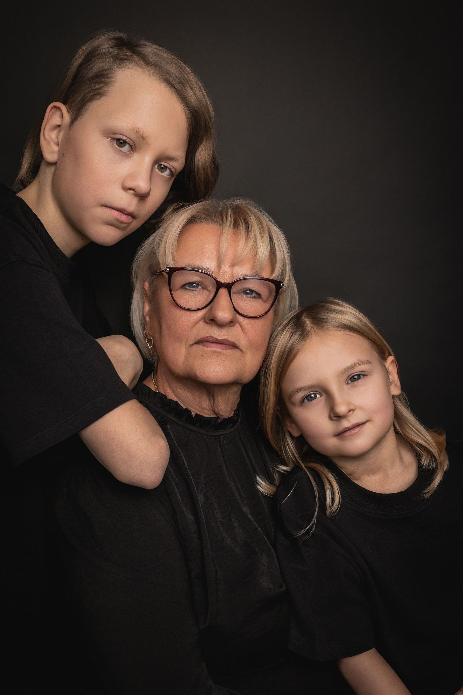 Eine Schwarz-Weiß-Porträtserie, die zärtliche Momente zwischen Familienmitgliedern vor einem dunklen Hintergrund zeigt.