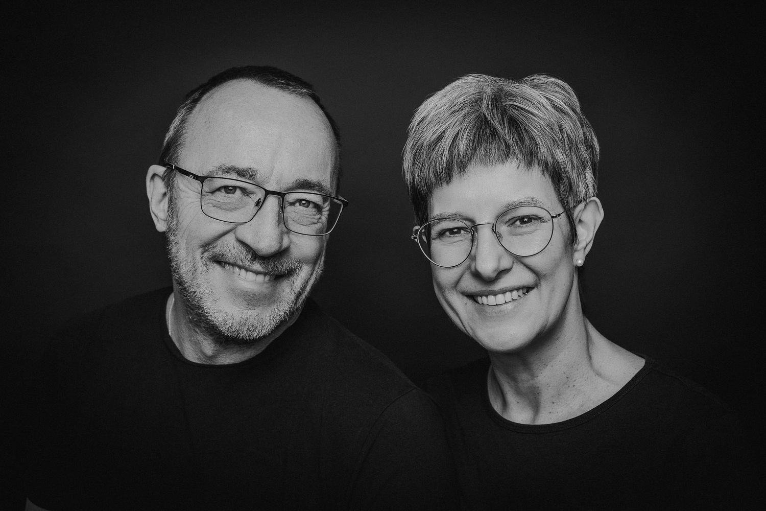 Black and white headshot portraits of people wearing glasses arranged in a horizontal row.