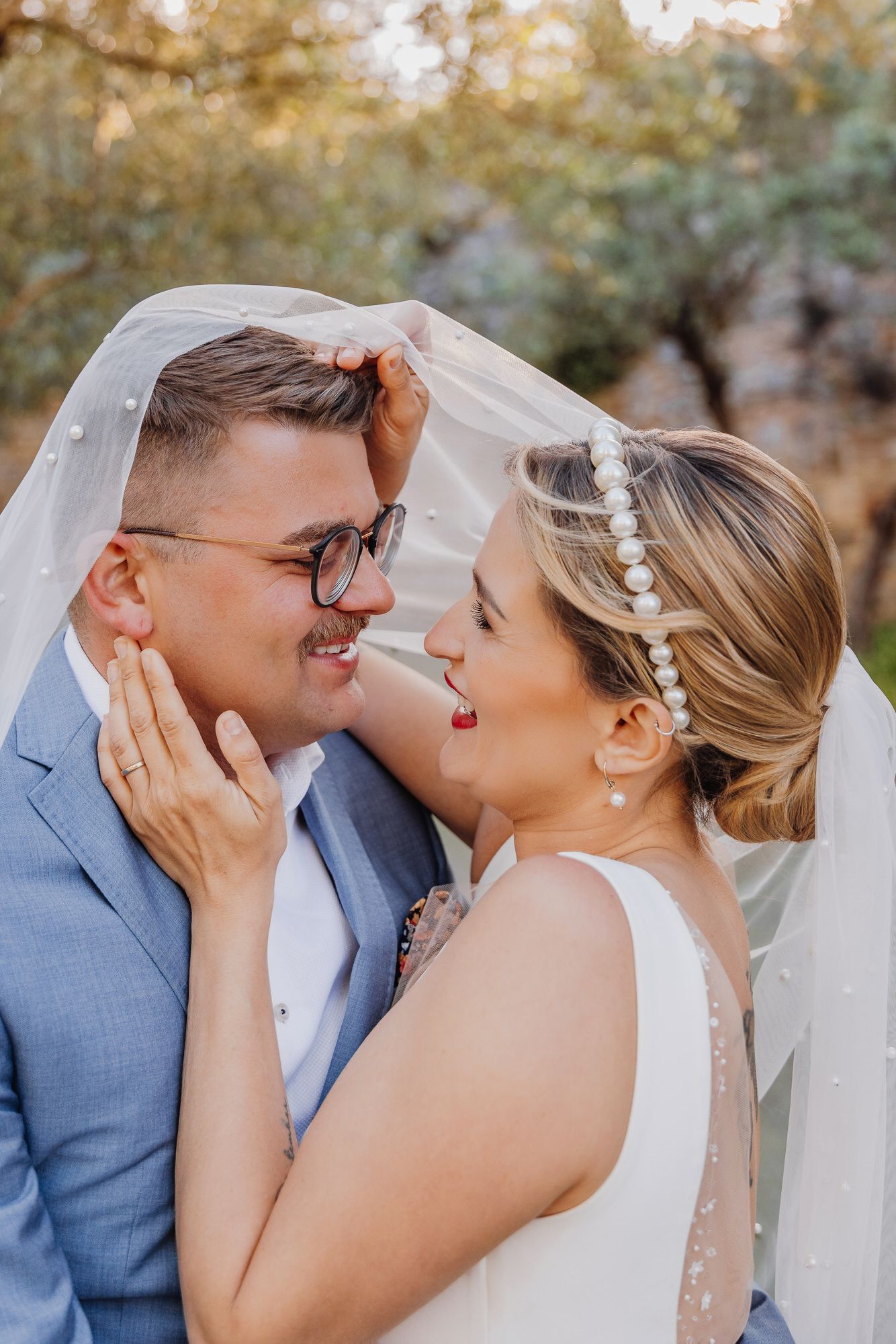 A bride and groom share a tender moment outdoors, both smiling and embracing in a series of romantic wedding photos.