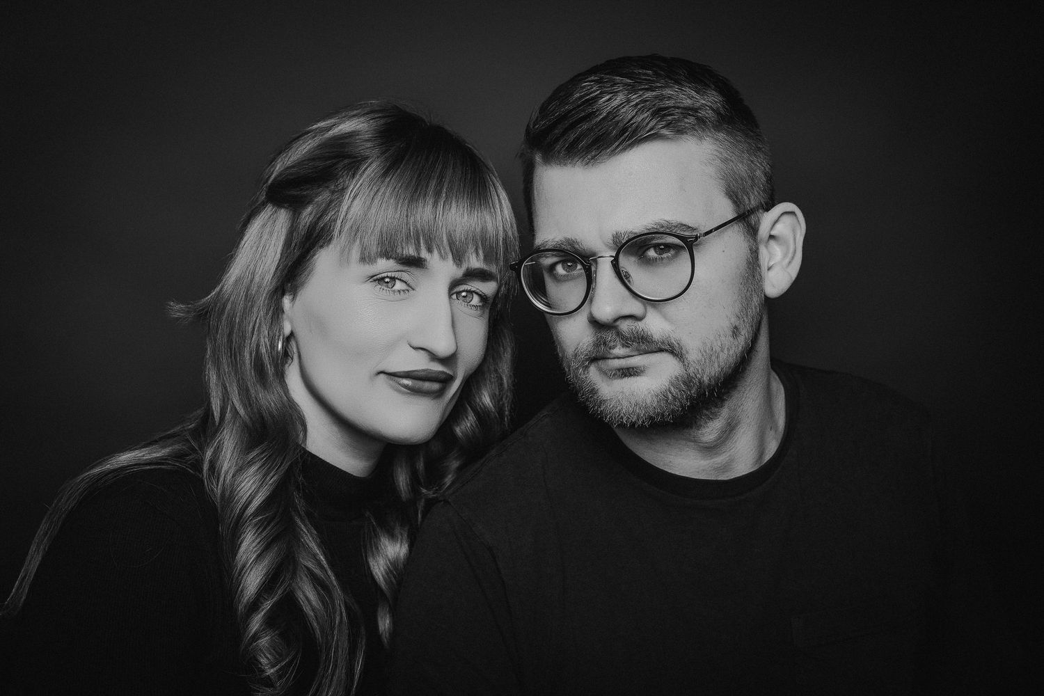A series of black and white portraits showing couples in intimate poses against dark backgrounds.