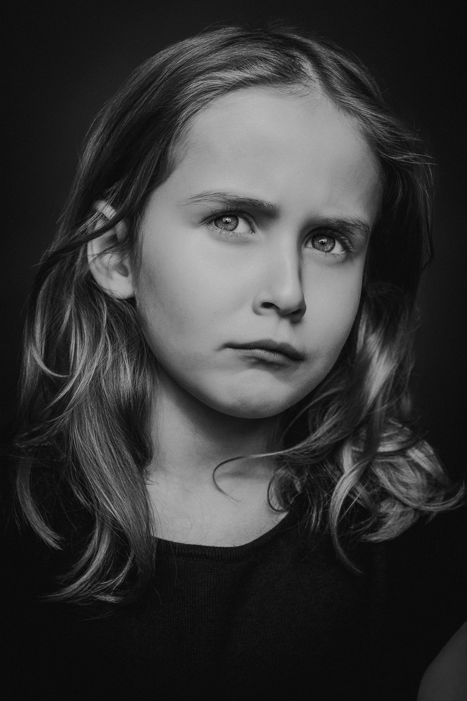 A dramatic black and white portrait series showing different angles of a child's face against a dark background.