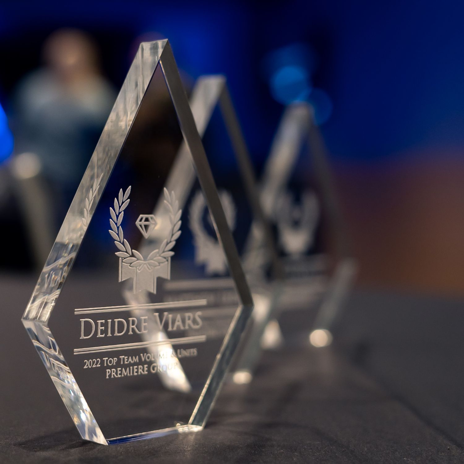 Crystal diamond-shaped awards engraved with Deidre Viars name displayed on a table at a formal ceremony.