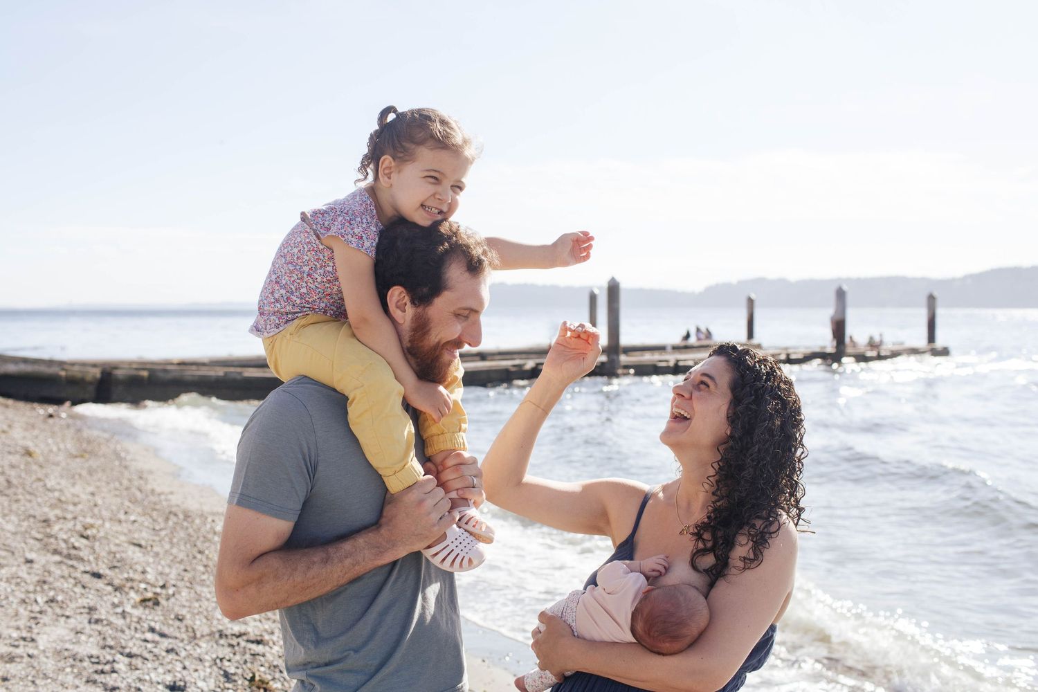 Seattle newborn photographer: A mother, father and their daughters laugh together during an outdoor newborn photo session