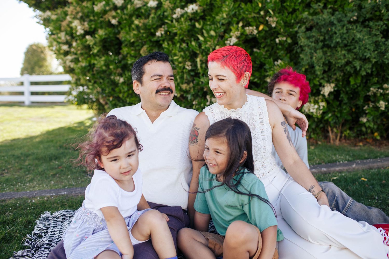 Everett family photographer: A mom and dad sit on the lawn with their three kids during an outdoor family photo session