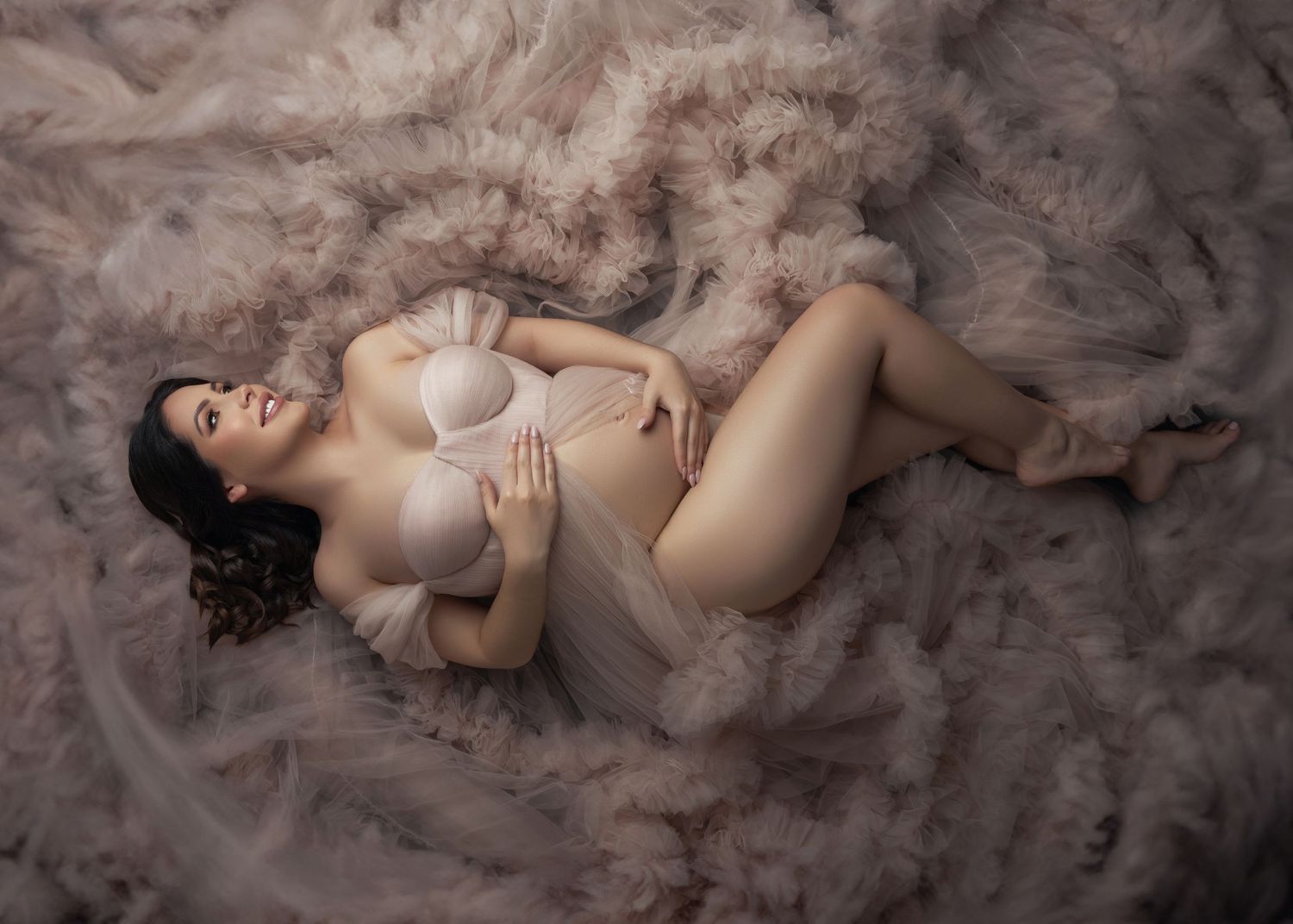 Artistic boudoir photo series showing a figure in white lingerie reclining on soft tulle fabric in romantic lighting.