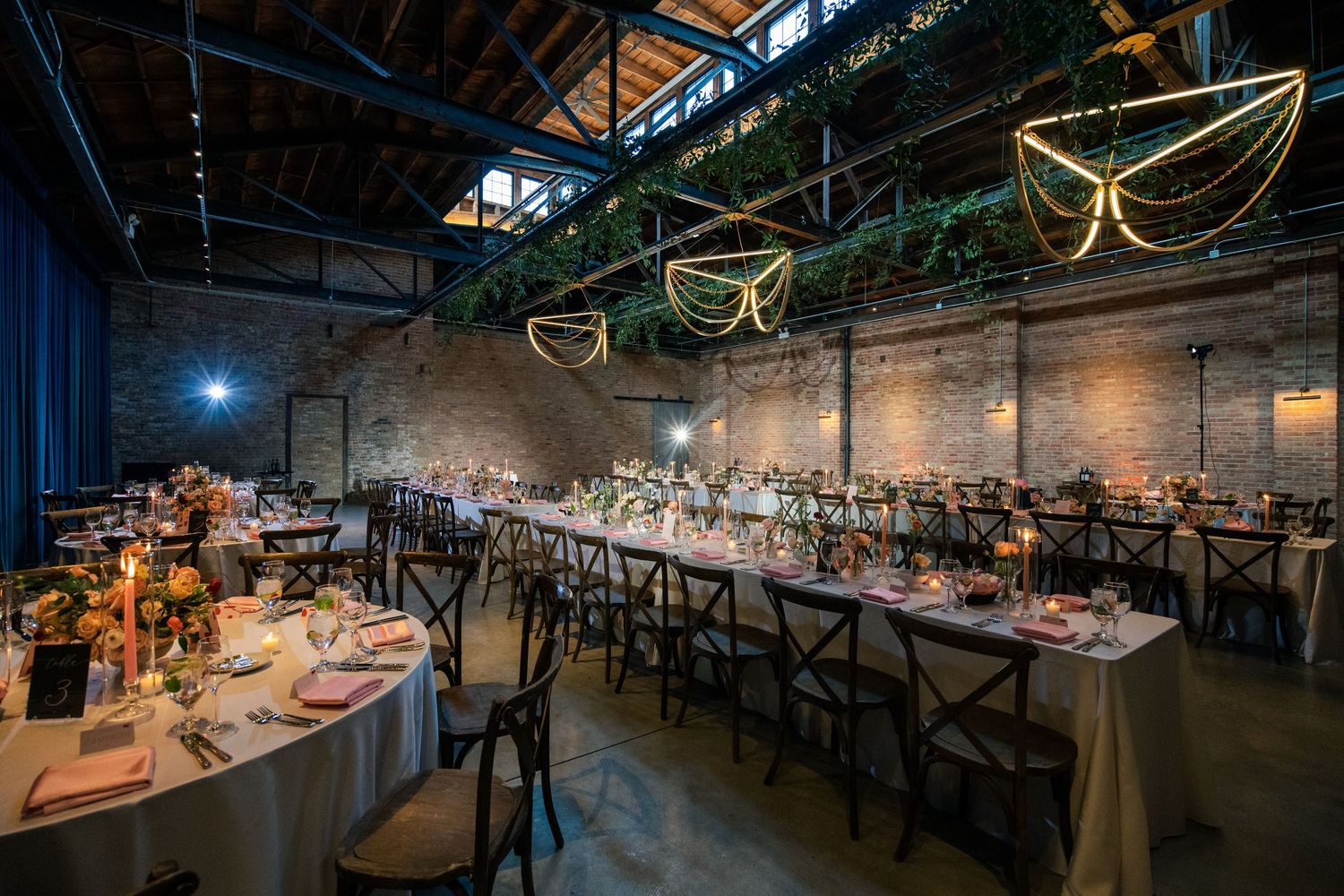 Modern industrial event space in Chicago decorated with string lights and long wooden tables for a dining setup.