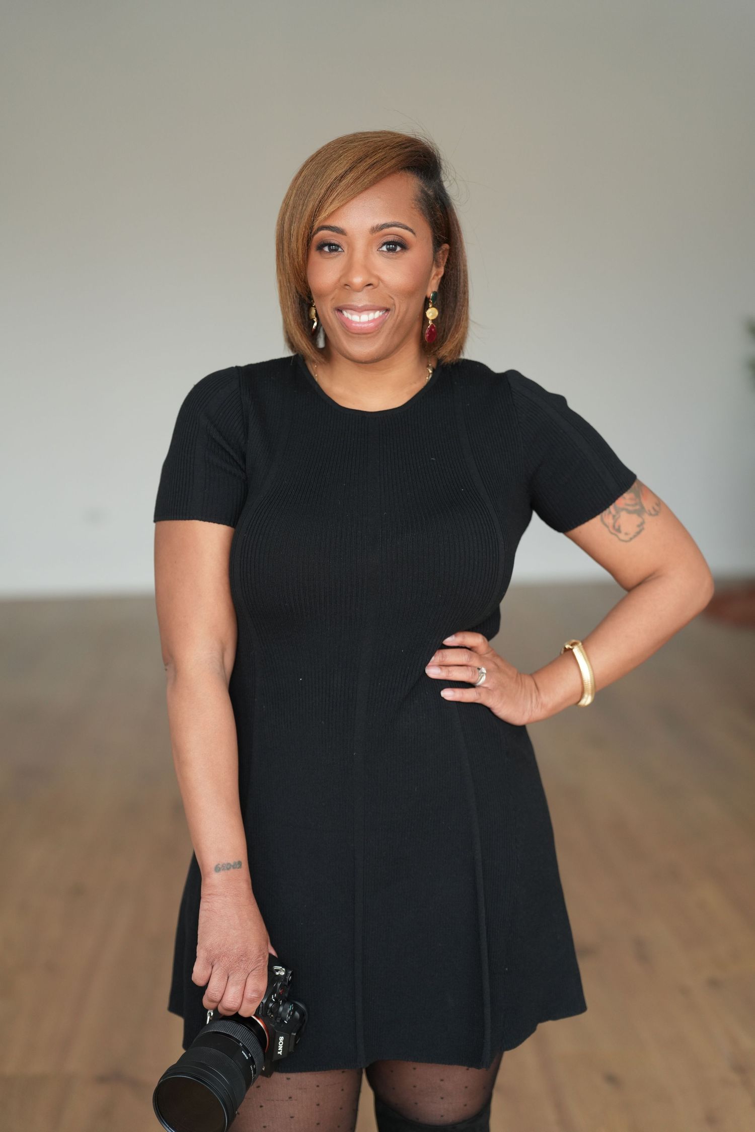 A person wearing all black poses confidently against a light background in a casual photo shoot.