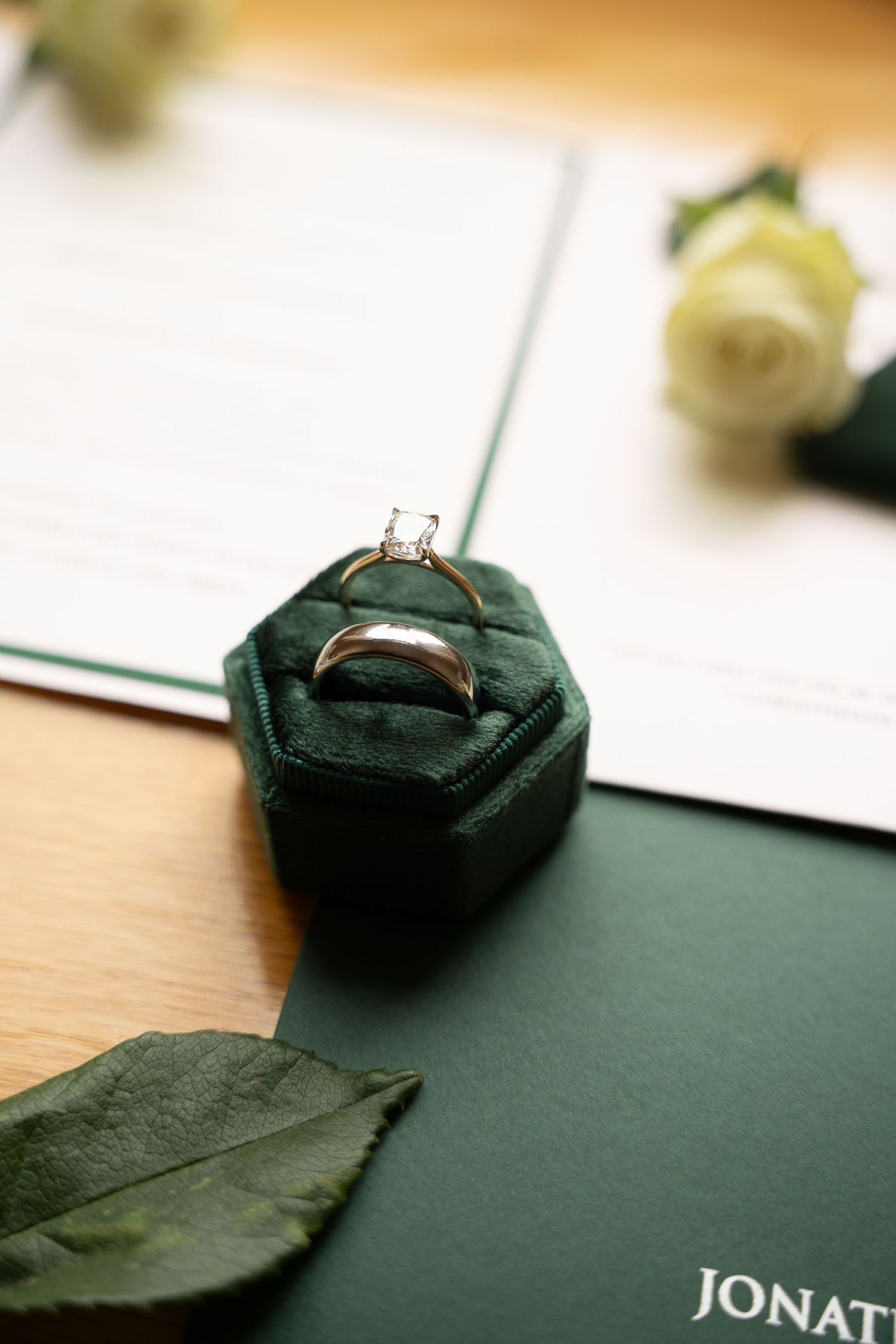 Wedding rings displayed on a dark velvet cushion against a minimalist backdrop.