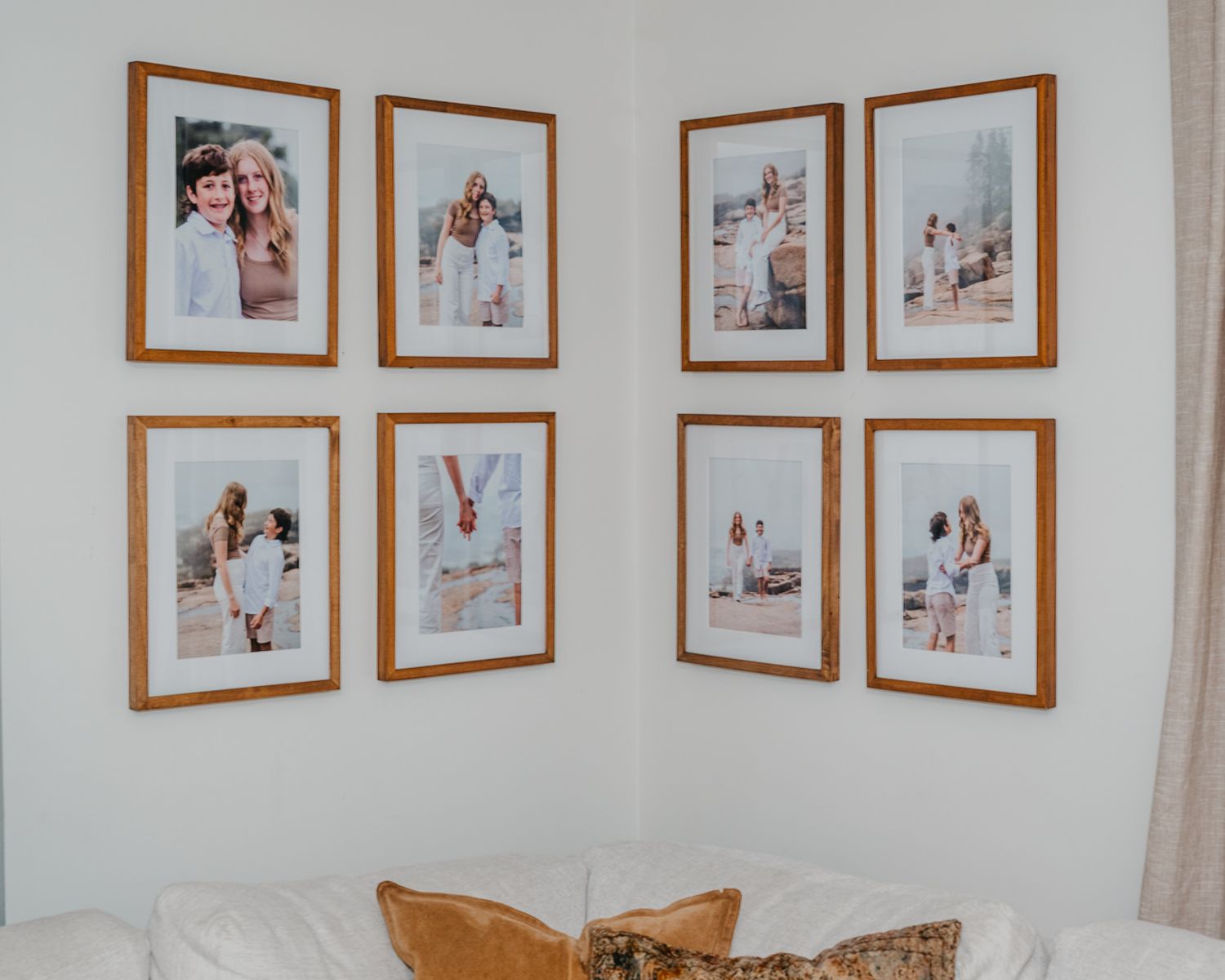 Gallery wall displaying framed wedding photographs in wooden frames arranged on white walls of a room.