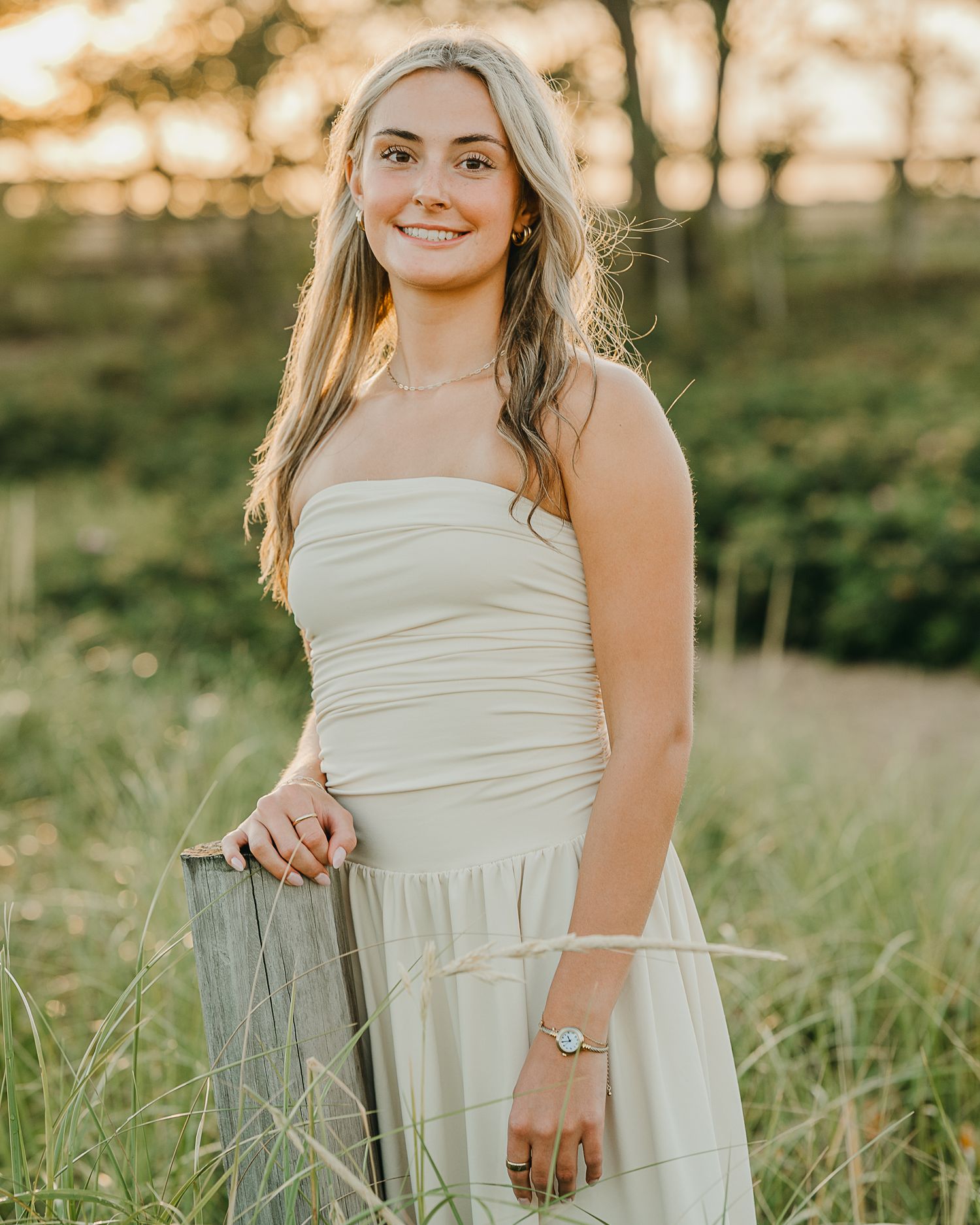 A white sleeveless dress is shown in detail against a natural outdoor setting during golden hour.