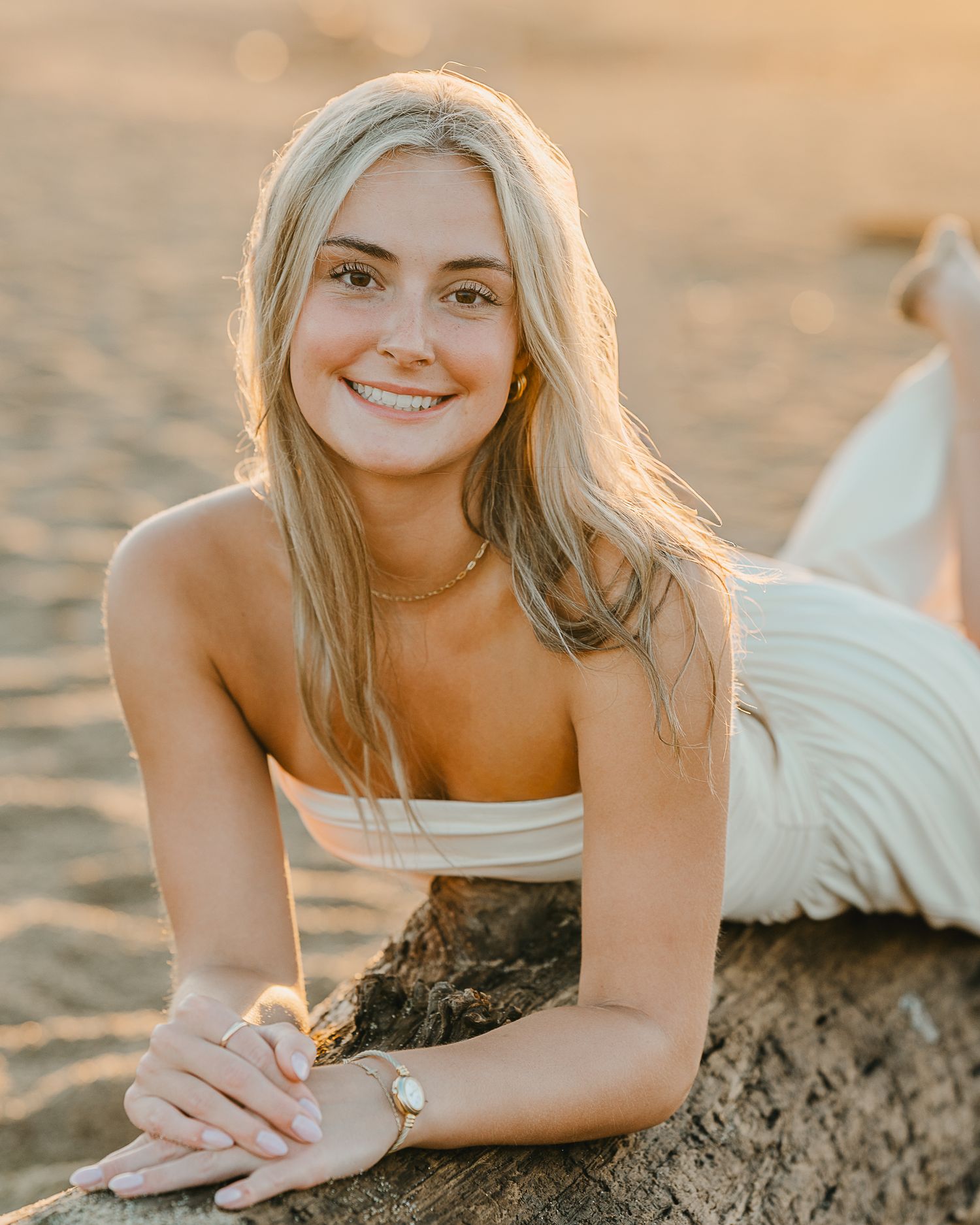 A person lying on sandy beach at golden hour with warm sunlight creating a dreamy coastal portrait.